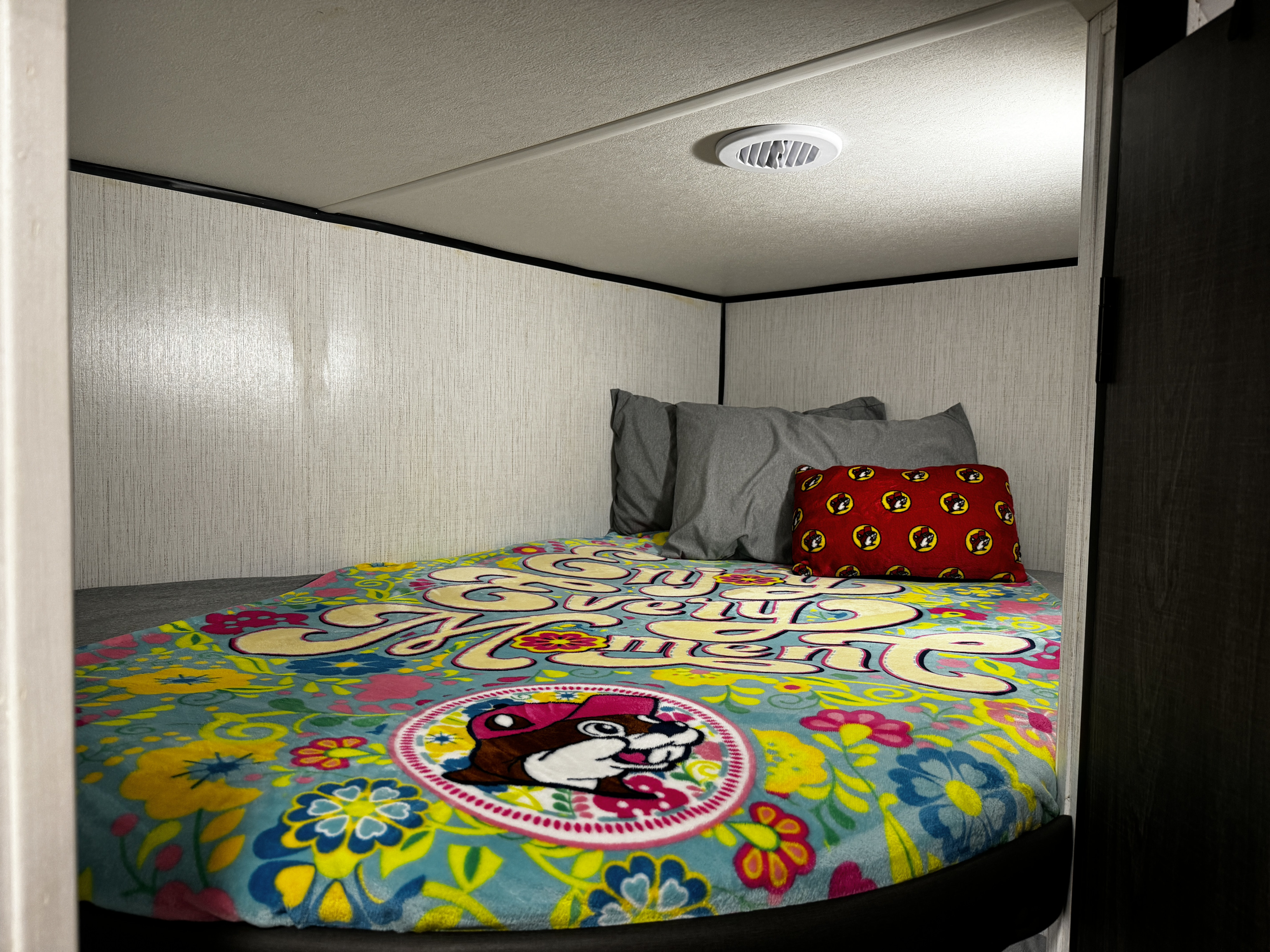 Cozy RV rental bunk bed with a vibrant Buc-ee's themed blanket and pillows. Perfect for a fun road trip!. Heartland RVs Trail Runner 2023