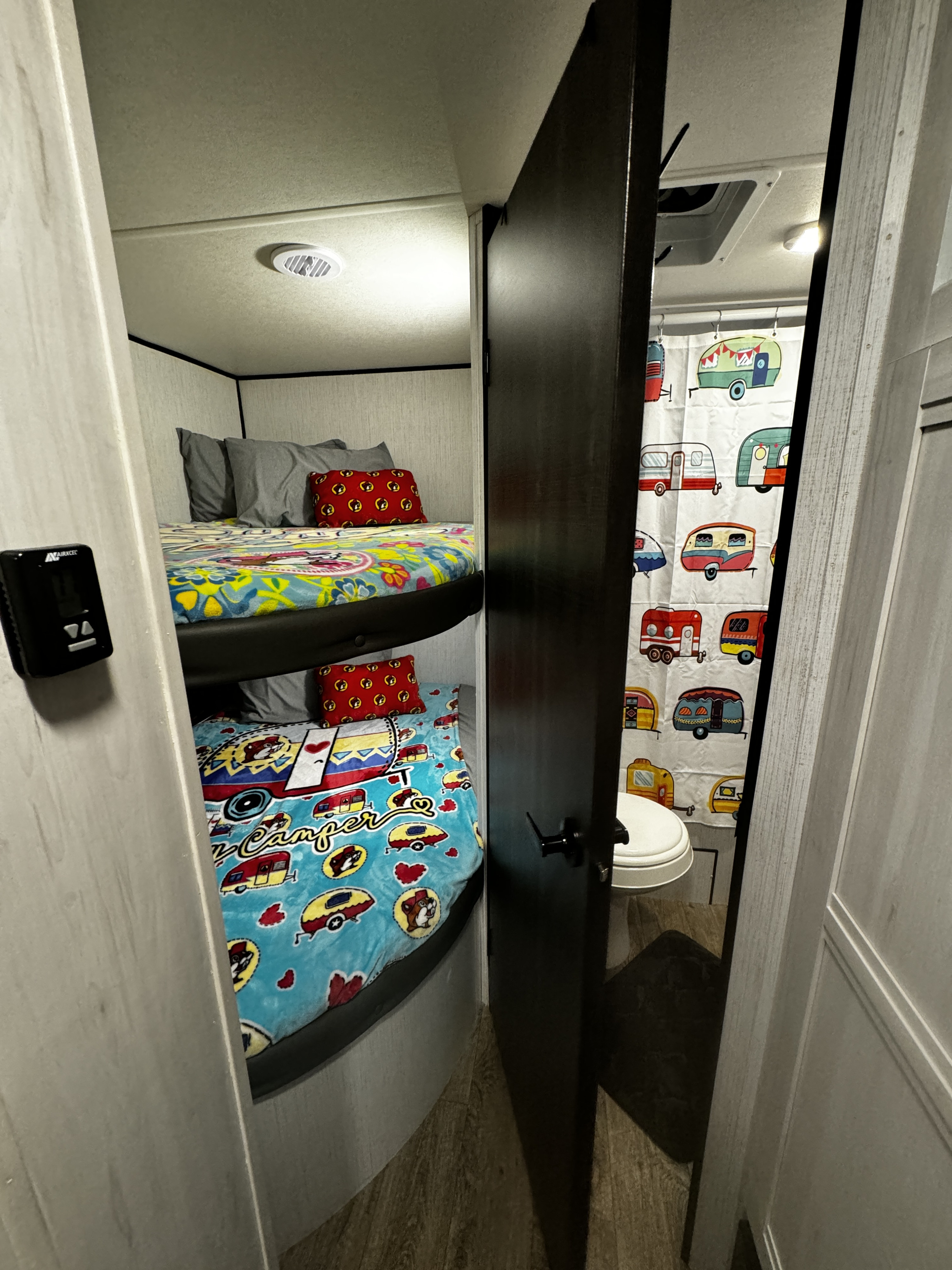 RV rental showing cozy bunk beds with colorful camper blankets and a compact bathroom with a charming camper shower curtain.. Heartland RVs Trail Runner 2023