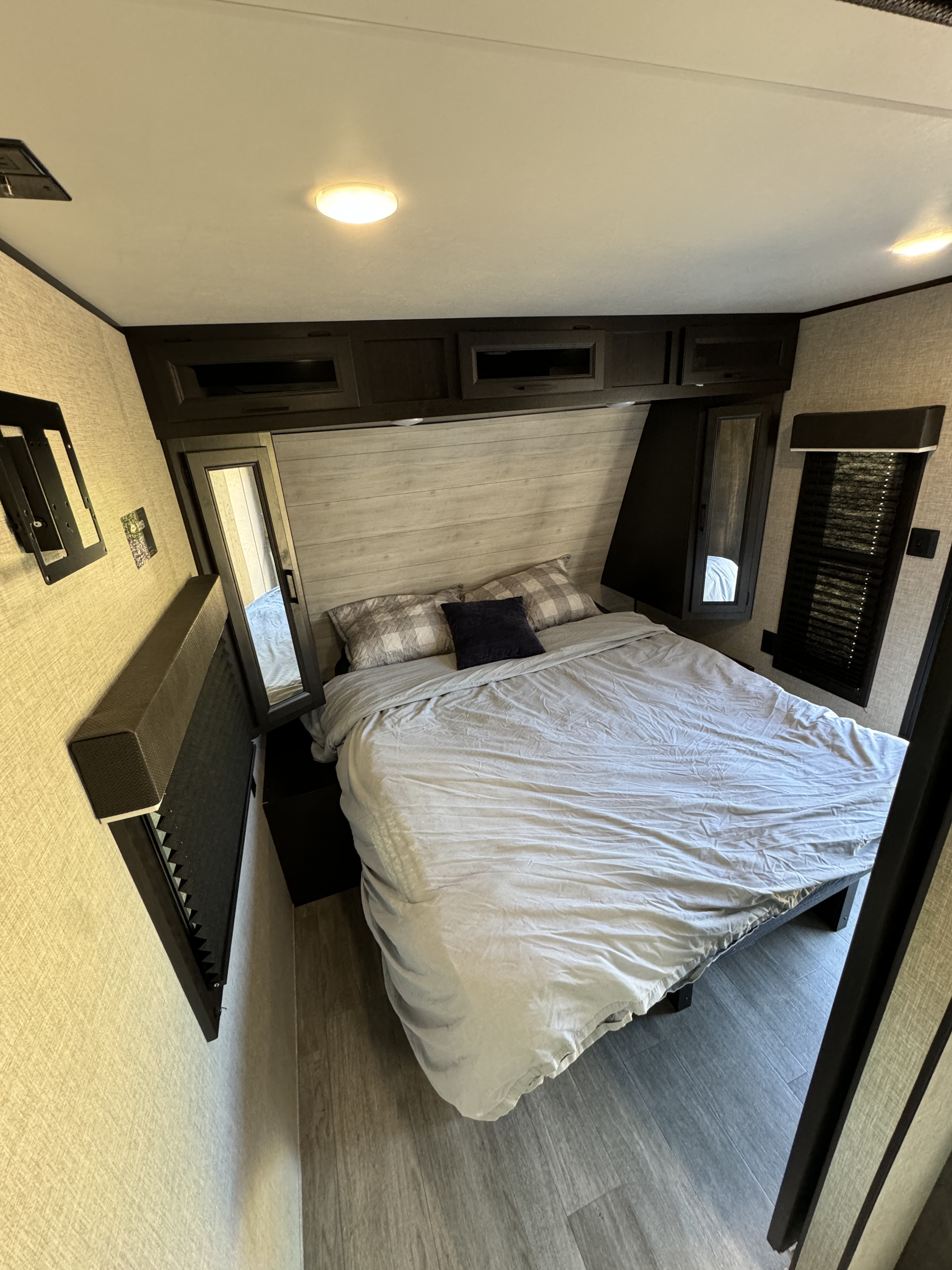 Well-appointed RV rental bedroom with a large bed, dark cabinets, a TV mount, and window blinds.. Jayco Jay Flight 2023