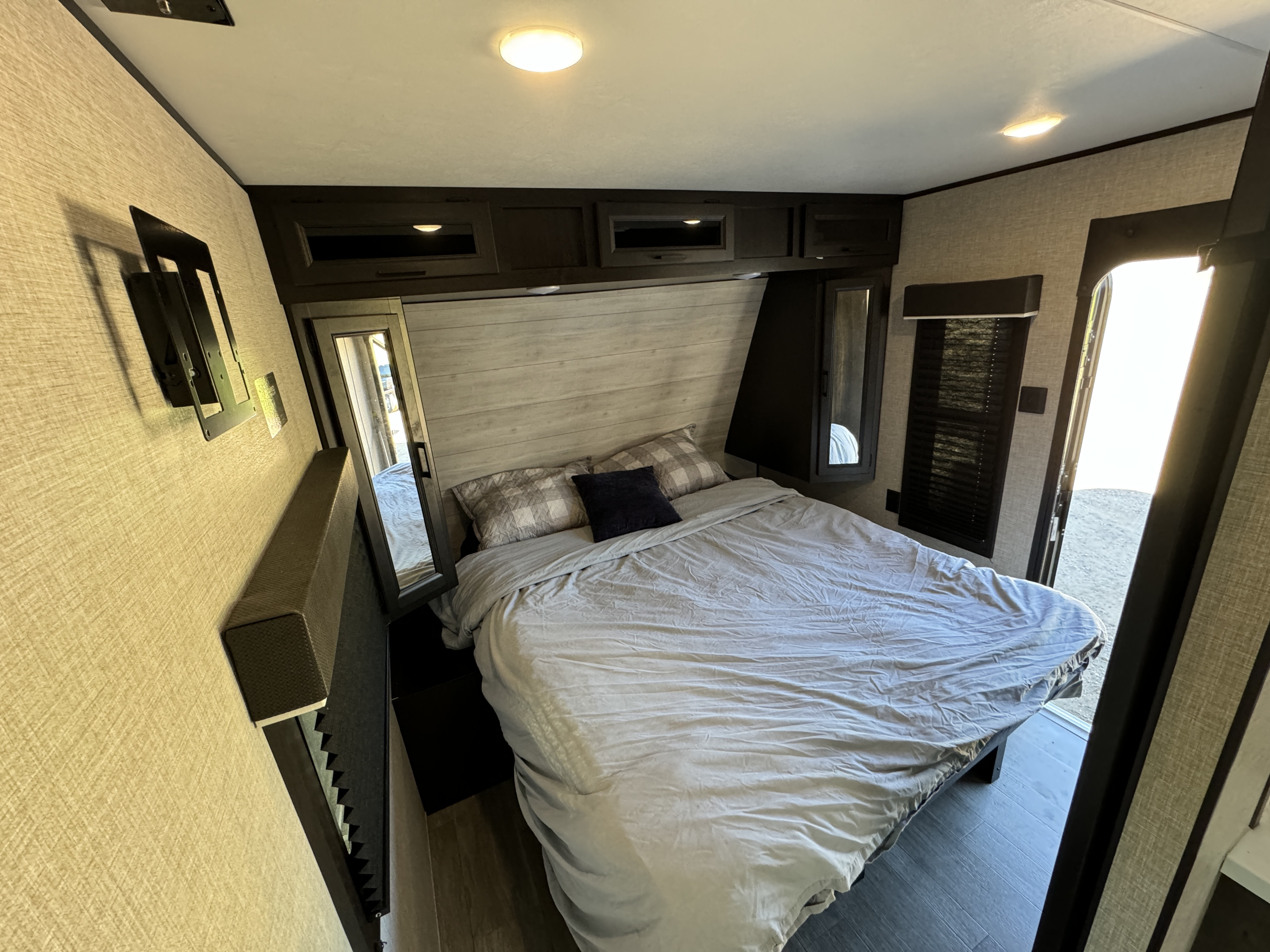 RV rental's cozy bedroom features a comfy bed, modern overhead cabinets, side mirrors, and a bright, inviting feel.. Jayco Jay Flight 2023