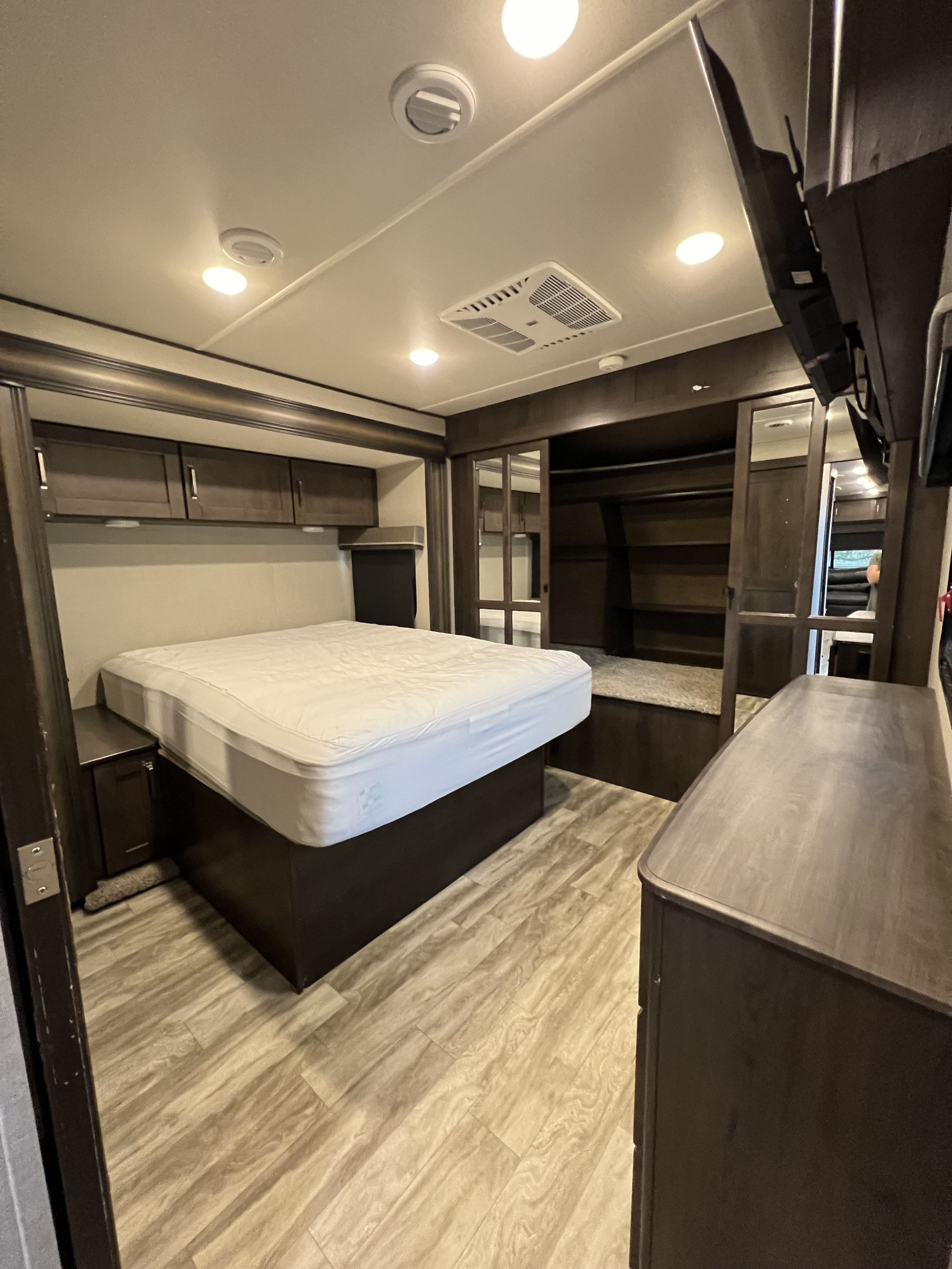 The bedroom has two closets, one large and one smaller. It also has a dresser and a wall-mounted TV. . Grand Design Reflection 2020