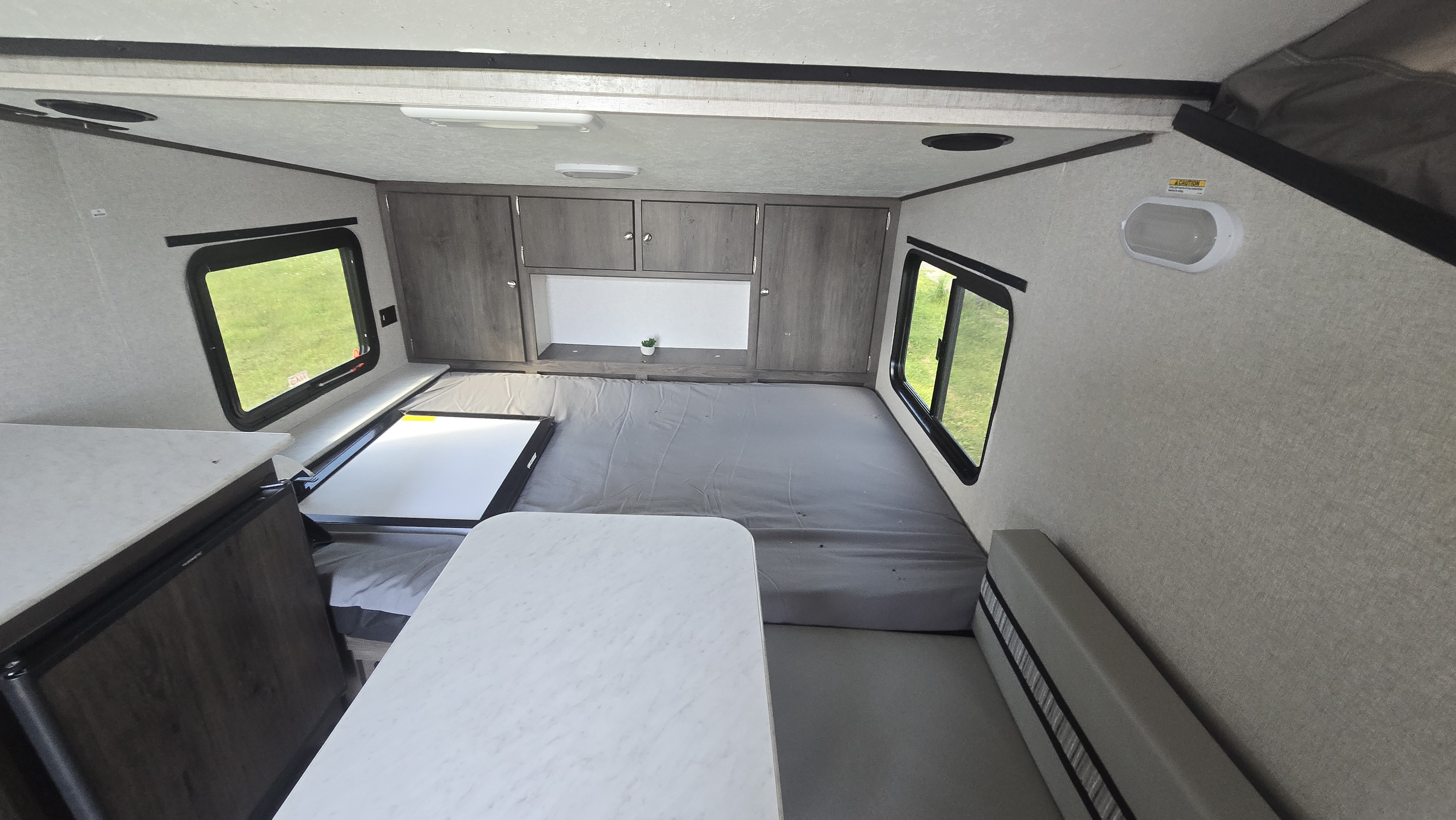Compact RV rental interior featuring a bed, storage cabinets, dinette table, and seating area.. Coachmen Clipper 2020