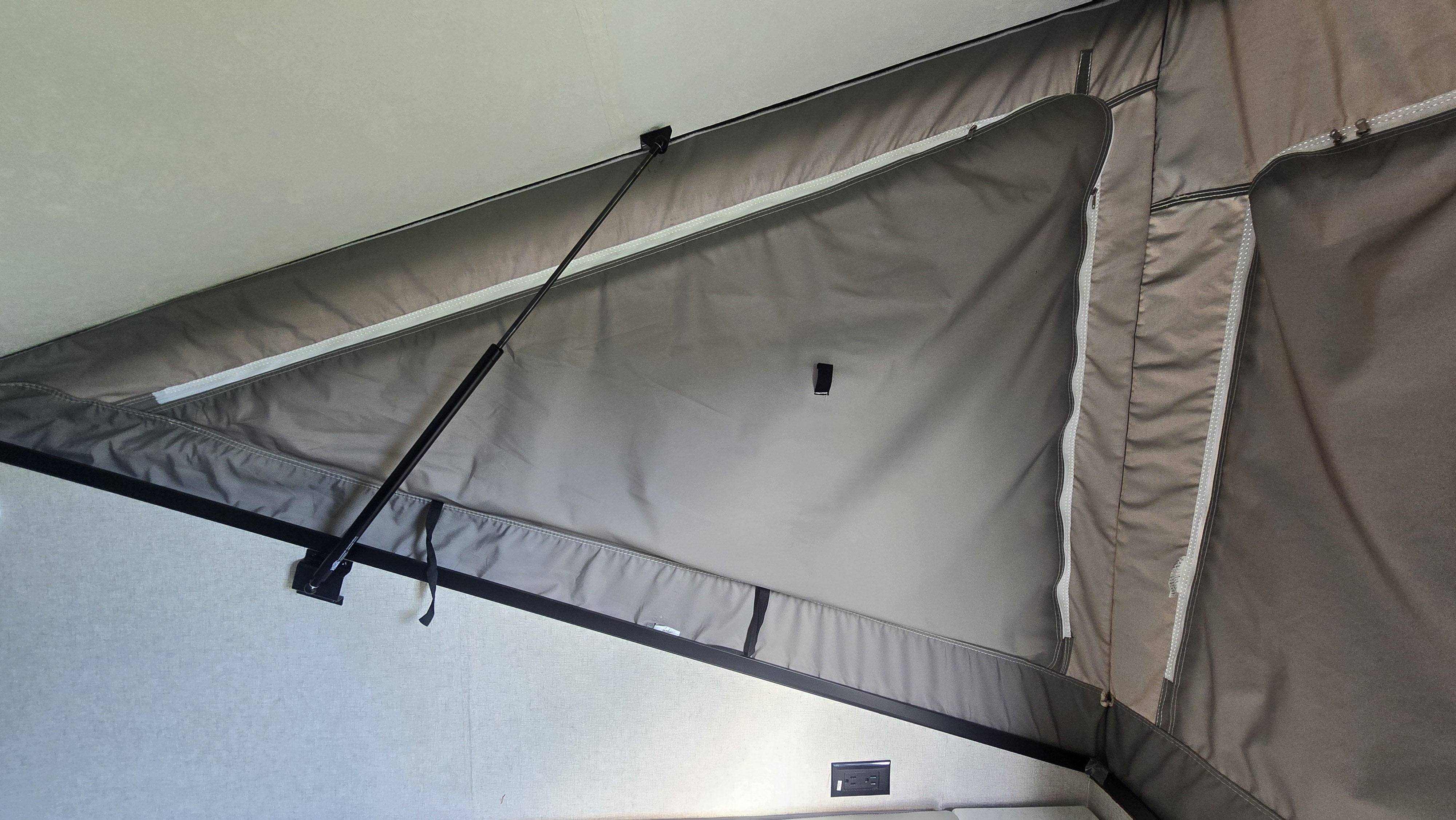RV rental interior: Pop-up camper bedroom with fabric walls, a supporting gas strut, and a power outlet.. Coachmen Clipper 2020