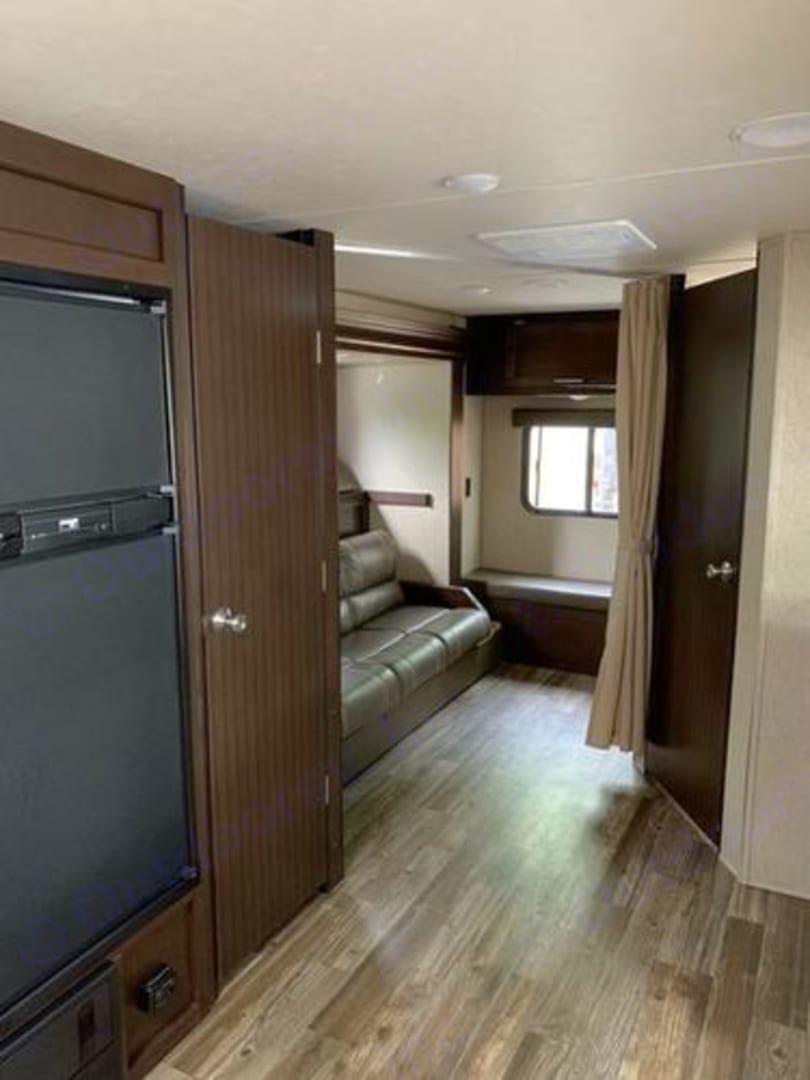 Spacious RV rental interior featuring a large refrigerator, dark sofa, and wood-look flooring. Perfect for your travels.. Forest River Cherokee Grey Wolf 2017