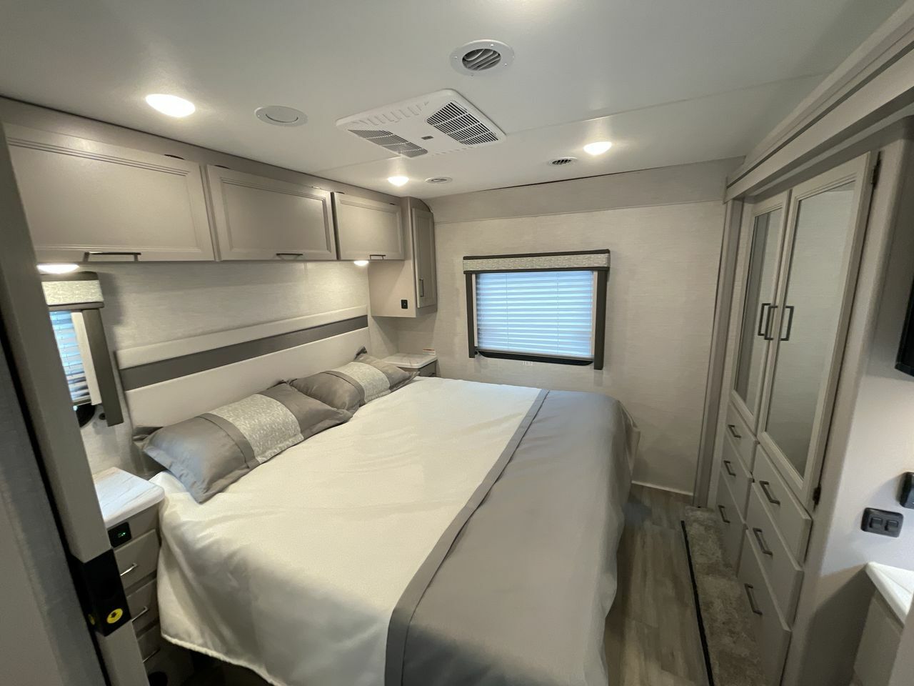 Experience comfort in this modern RV rental bedroom, featuring a large bed, built-in storage, and thoughtful design.. Thor ACE 2024