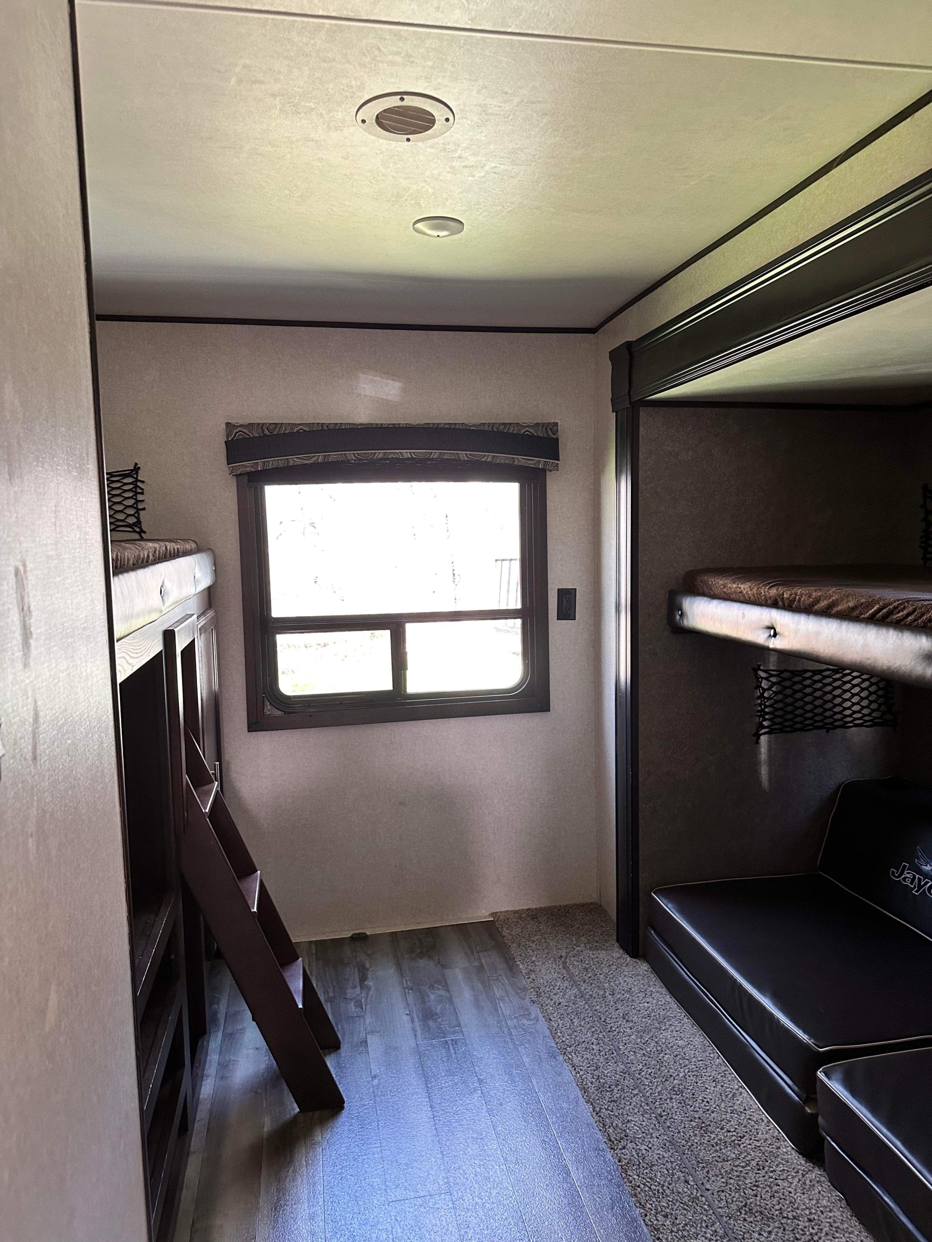 Spacious rv rental interior showcasing bunk beds with a ladder, a window, and a comfortable seating area.. Jayco Jay Flight 2019