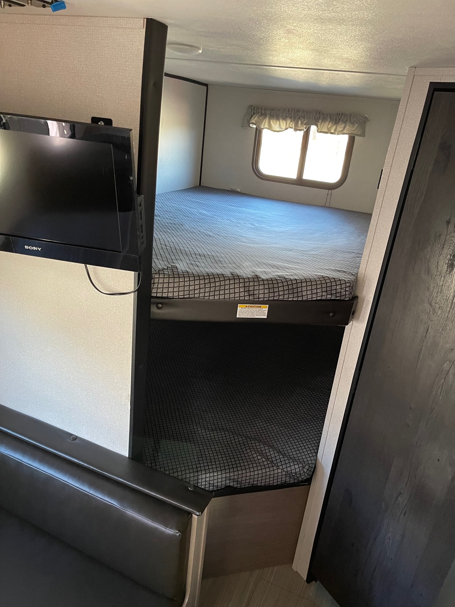 This RV rental showcases bunk beds, a TV, and seating, providing a cozy travel space.. Gulf Stream Hideout 2021