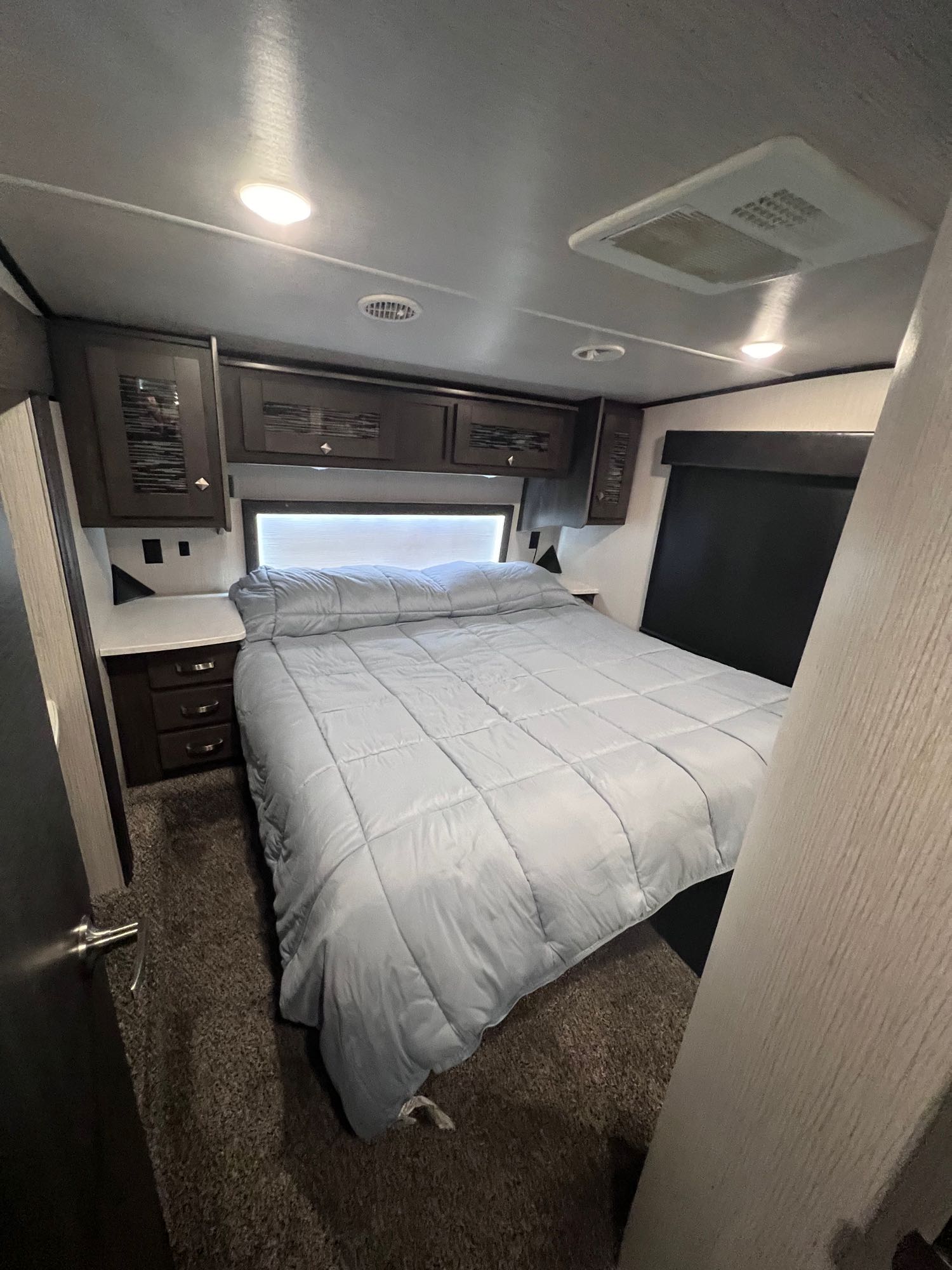 Cozy RV bedroom with a comfortable bed, overhead cabinets, and soft lighting, perfect for your next RV rental adventure.. Heartland RVs Road Warrior Toy Hauler 2021