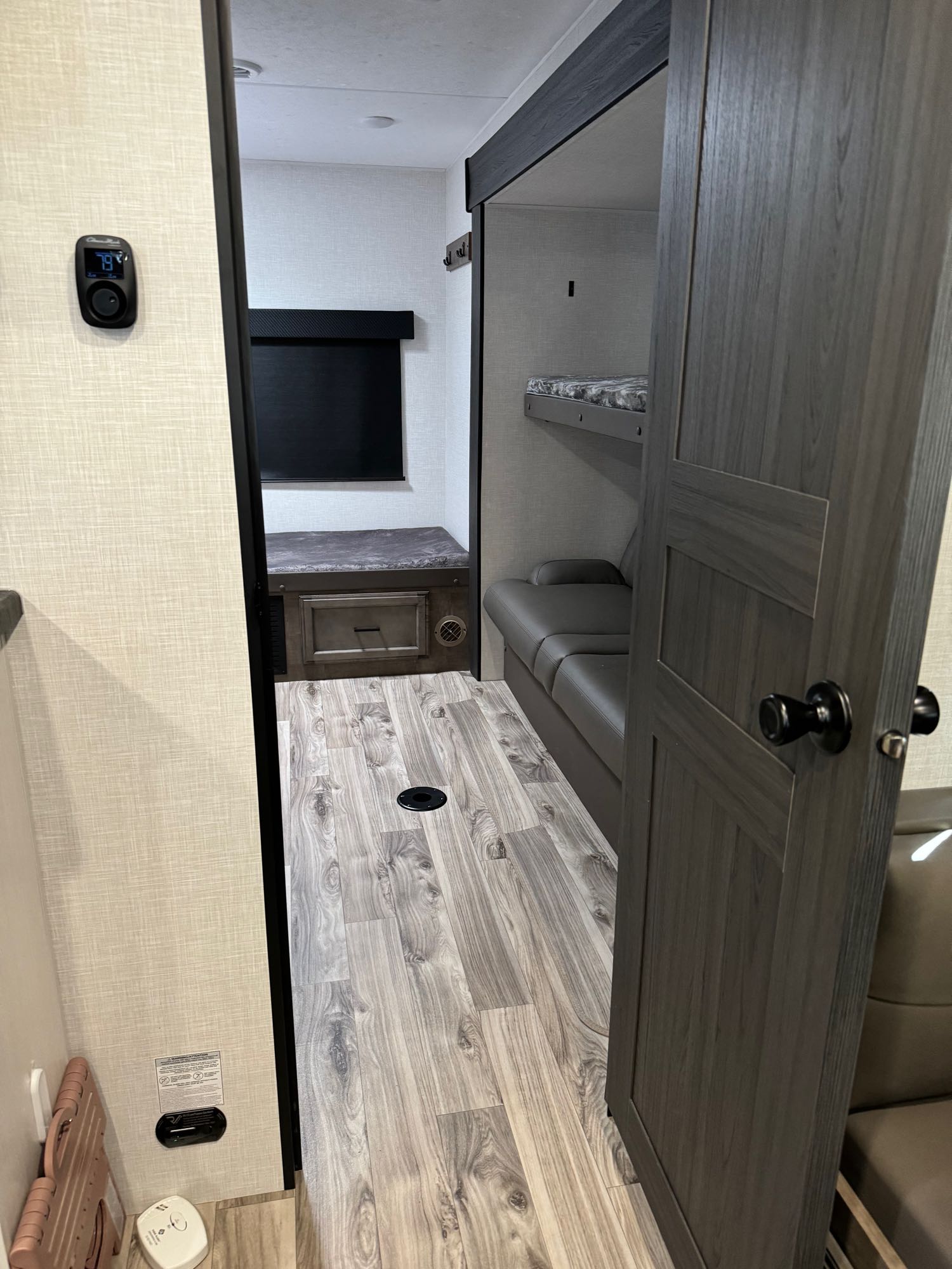 RV rental interior showcasing a bunk room with beds, a lounge area, wood-look floor, and a thermostat (79°).. sport trek vic 333 2024