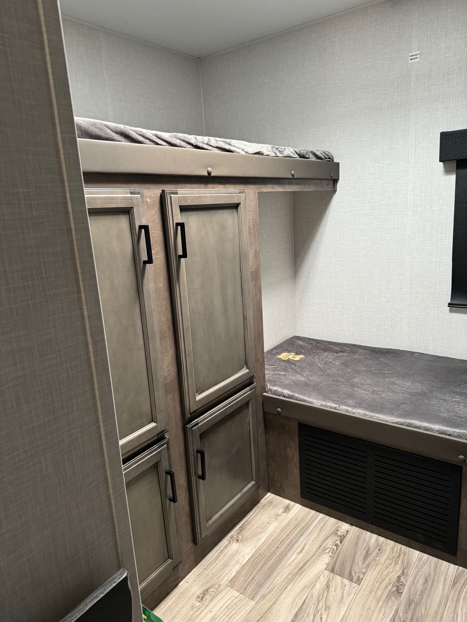 RV rental: Compact RV bunk beds with storage cabinets, featuring soft gray blankets and wood-look flooring.. sport trek vic 333 2024