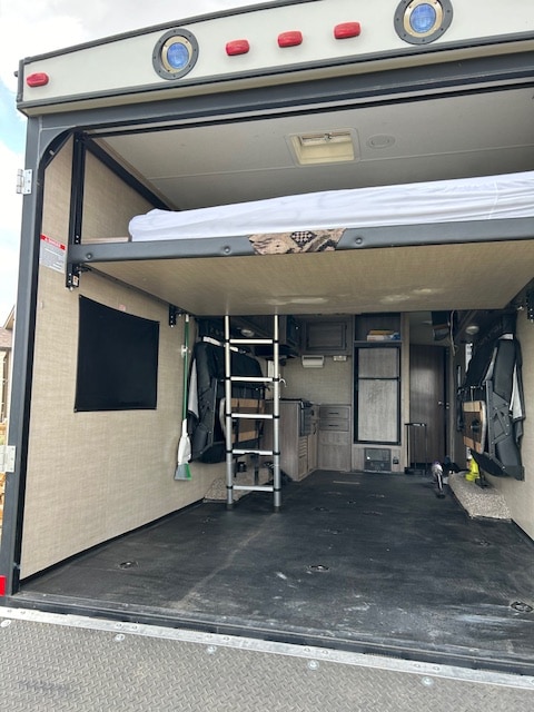 Experience adventure with this RV rental: an open toy hauler showcasing a spacious cargo area, raised bed, and kitchen.. Pacific Coachworks Tango 2017