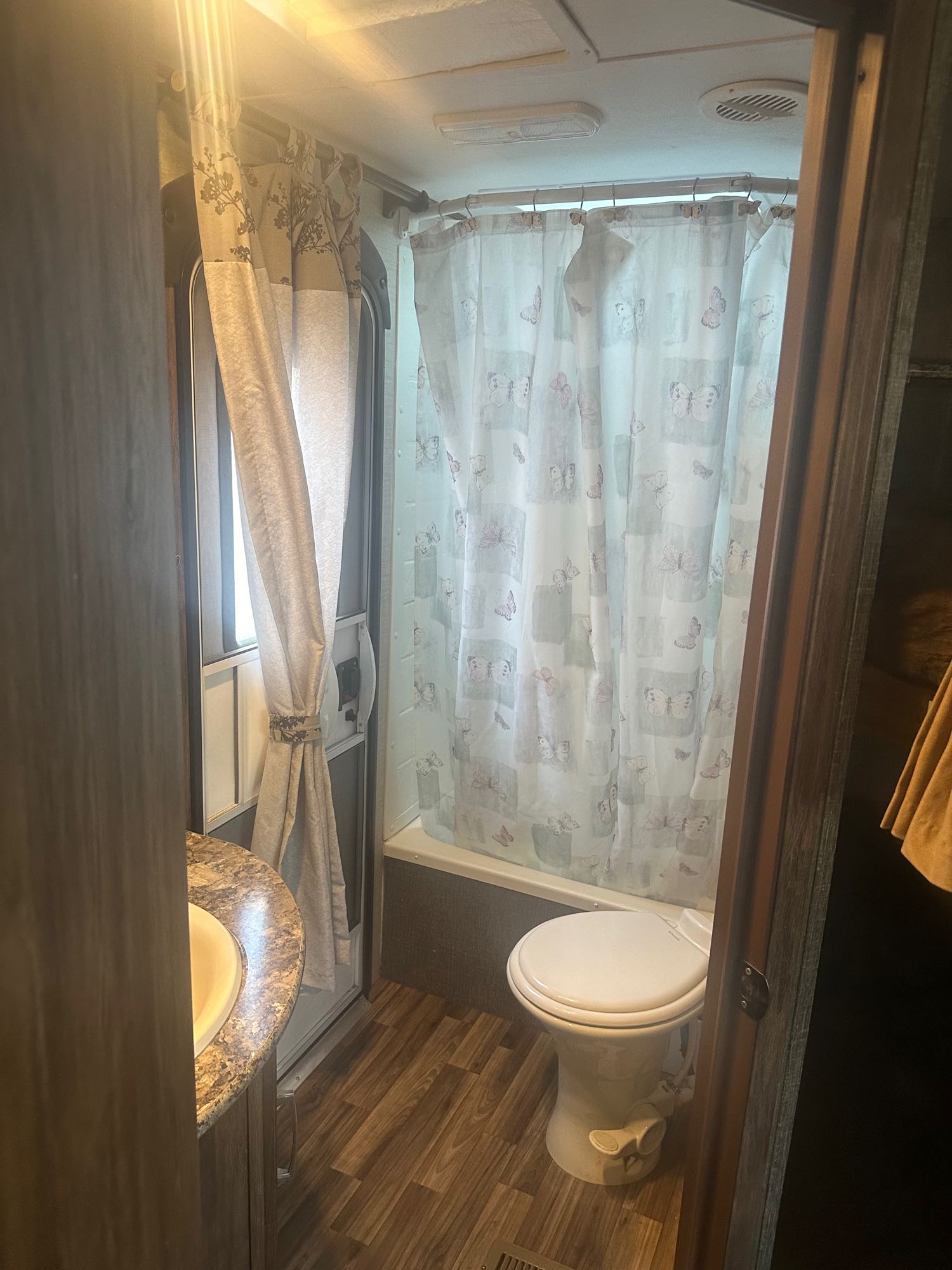 RV rental bathroom interior: white toilet, tub shower with butterfly curtain, and sink vanity.. Keystone RV Cougar 2016