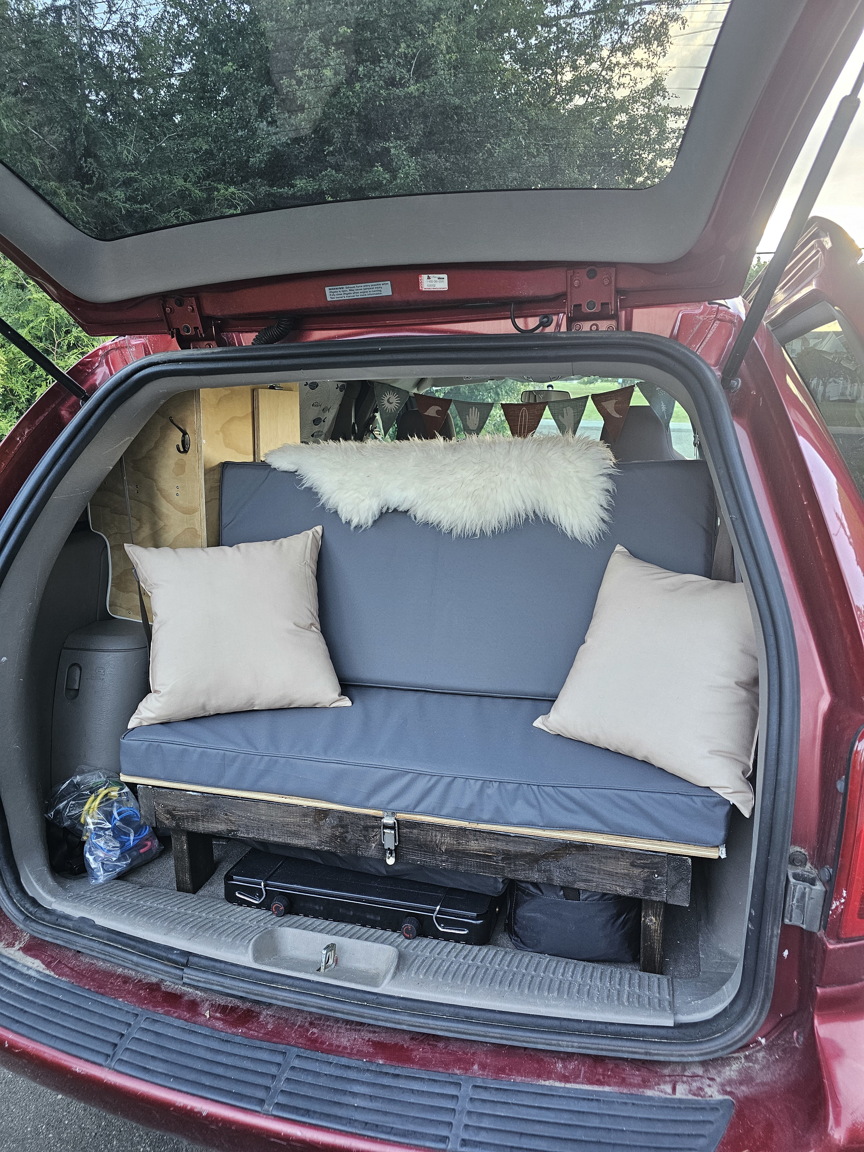 This custom minivan conversion features a cozy camper bed, ideal for an RV rental or road trip adventure. Interior view.. Dodge Caravan 2003