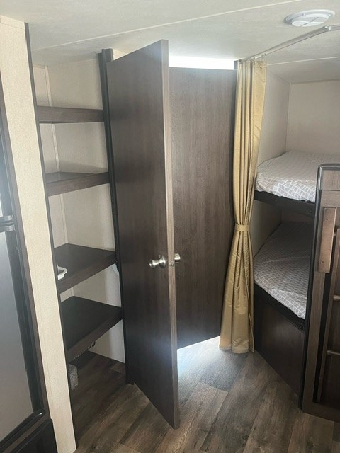 RV rental interior: a bunk bed area with privacy curtain and a nearby closet with shelves for storage.. Forest River Salem Cruise Lite 2019