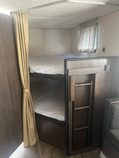 Explore this RV rental's cozy bunk beds, complete with a ladder, window, and privacy curtain.. Forest River Salem Cruise Lite 2019