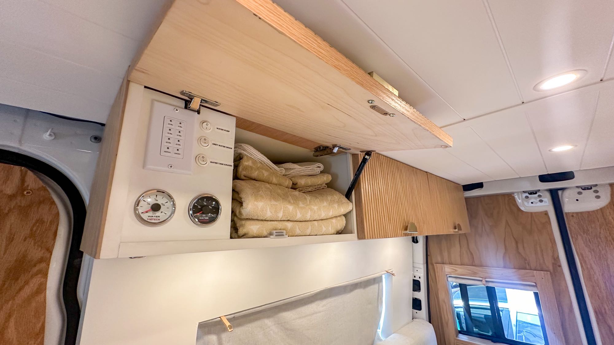Inside this RV rental van, notice the practical overhead storage, water tank gauges, and utility controls.. Mercedes-Benz Sprinter 2020