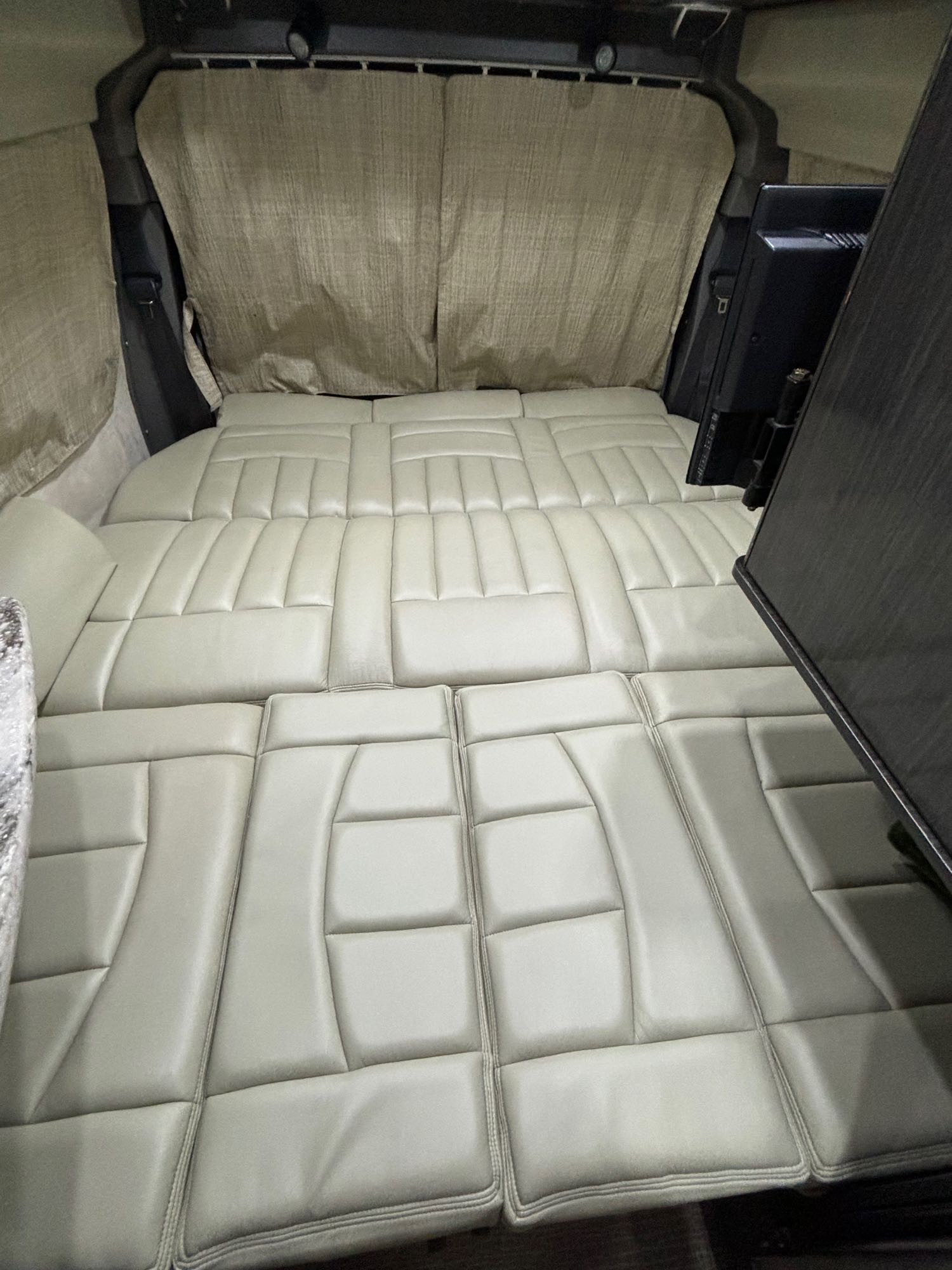 Spacious RV rental interior featuring a custom light gray tufted mattress bed, ideal for comfortable travel.. Airstream Avenue 2012