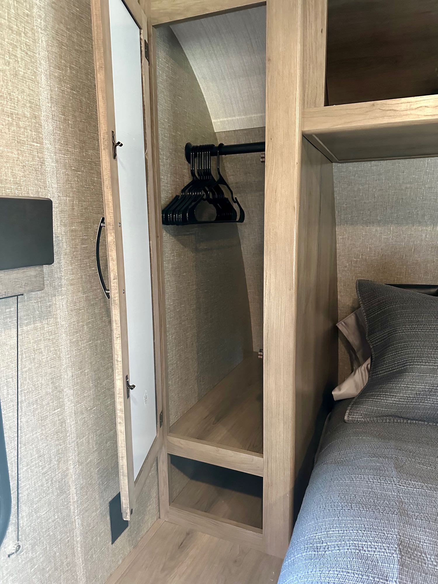 RV rental bedroom with compact closet, hanging space, and storage shelves next to the bed.. Grand Design Transcend Xplor 2020