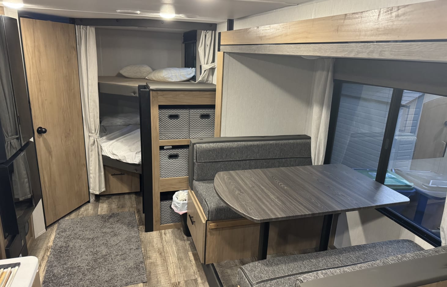 Comfortable RV rental interior with bunk beds, a dinette, and storage bins, ready for family adventures.. Forest River Campsite Reserve 26CJ 2024