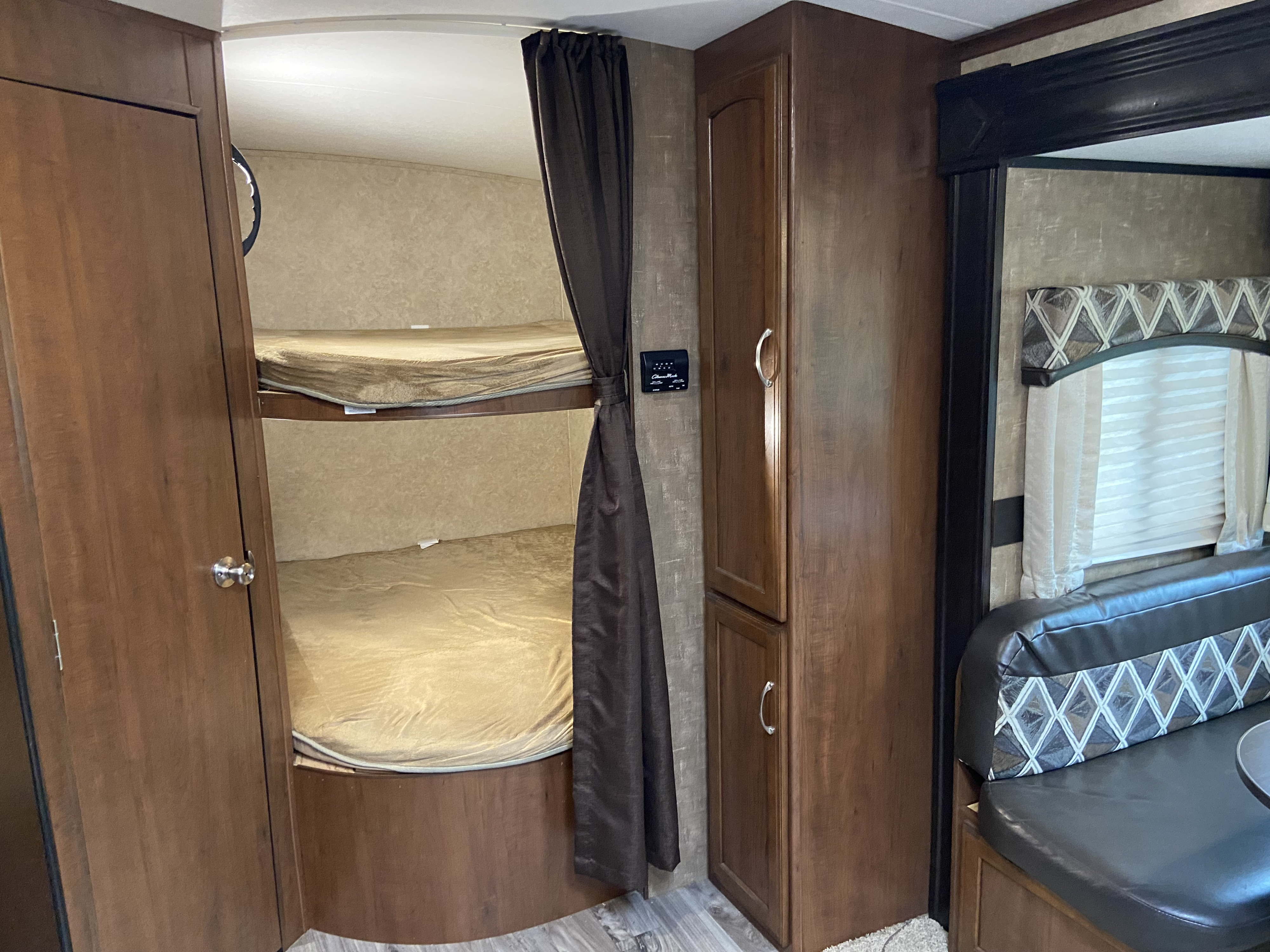RV rental interior featuring comfortable bunk beds, a storage cabinet, and a cozy dinette seating area.. Jayco White Hawk 2017