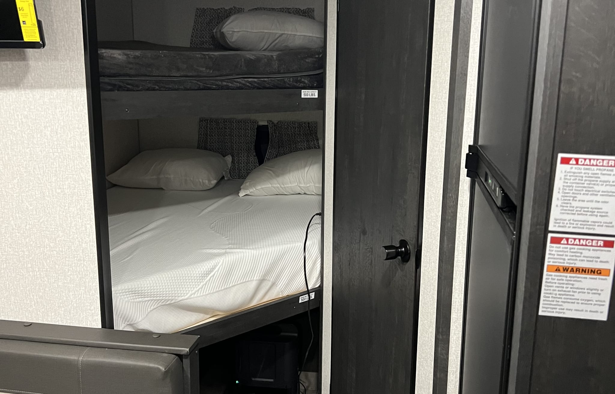 This RV rental's interior features cozy bunk beds and vital safety warnings for propane and carbon monoxide.. KZ Sportsmen 26BHSE 2022