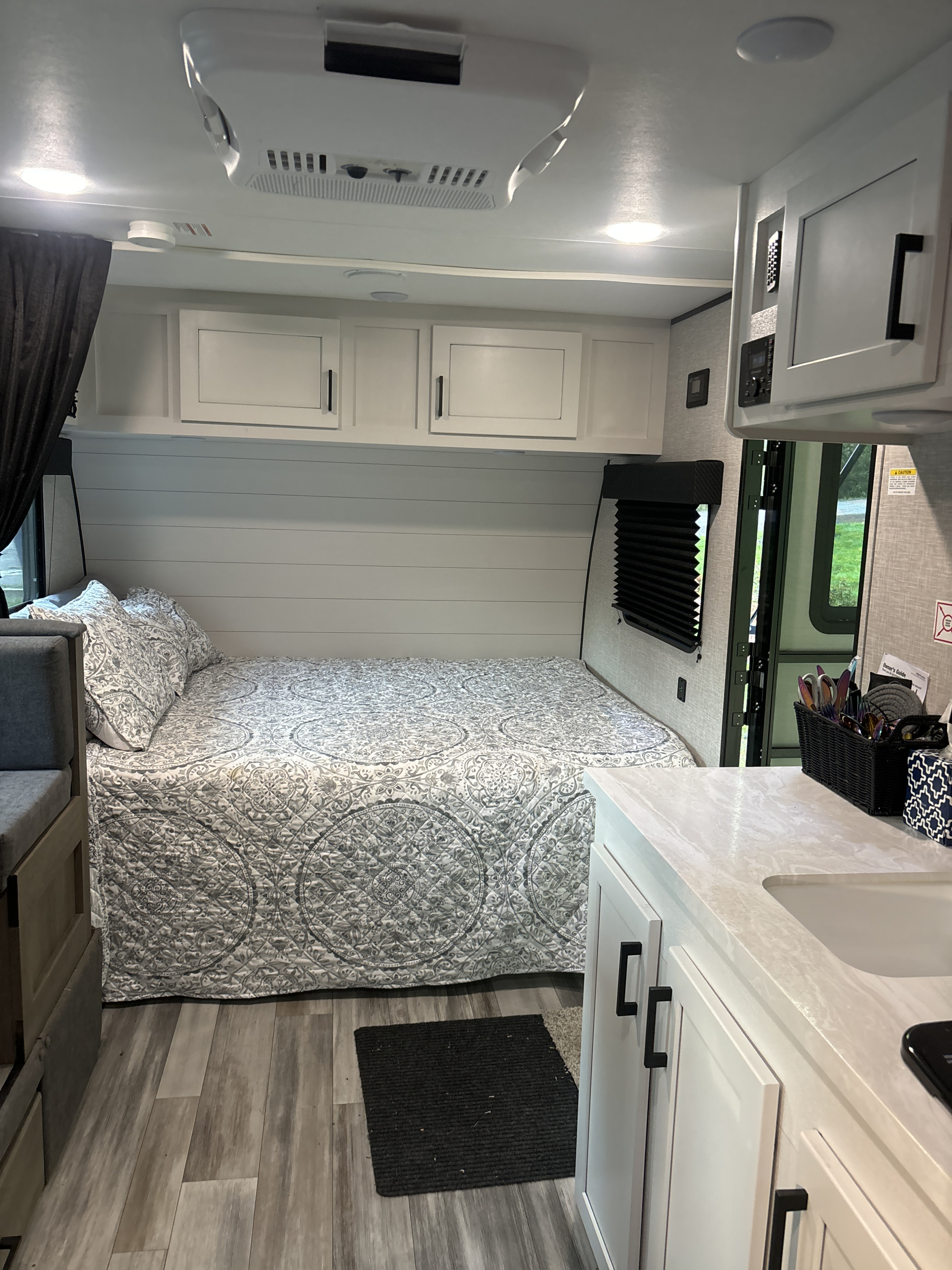 Modern rv rental interior: light bedroom with patterned bedding, built-in seating, kitchenette, and overhead cabinets.. Jayco Jay Flight SLX 2024