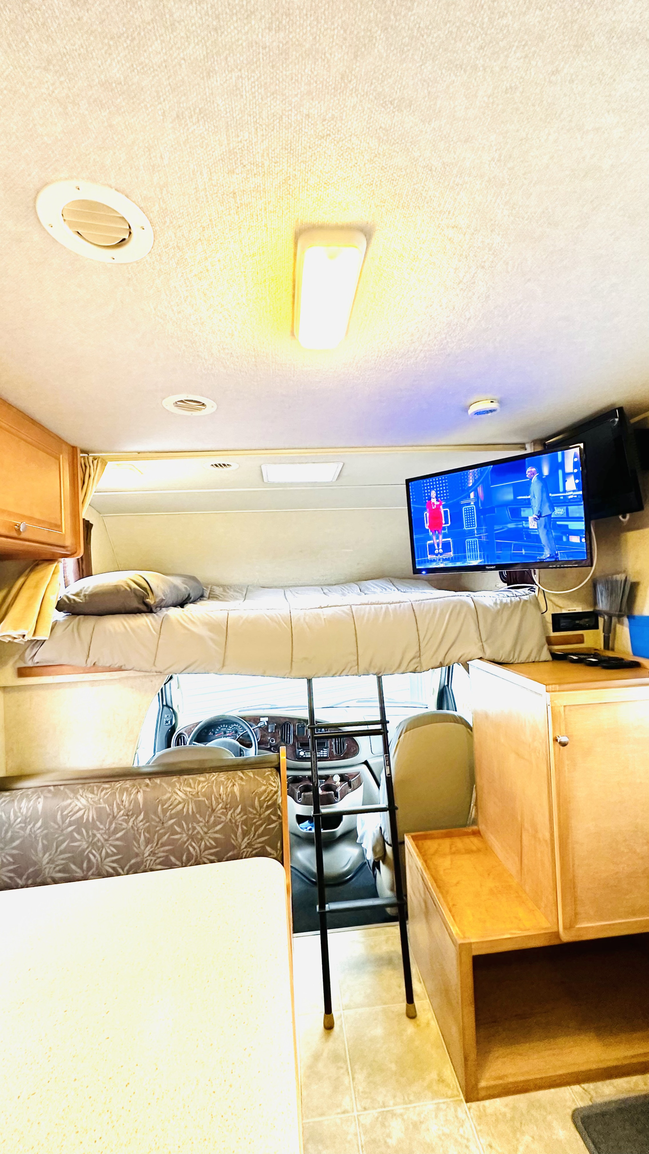 Experience an RV rental: interior with over-cab bed, TV, dinette, and driver's area.. Winnebago Chalet 2009