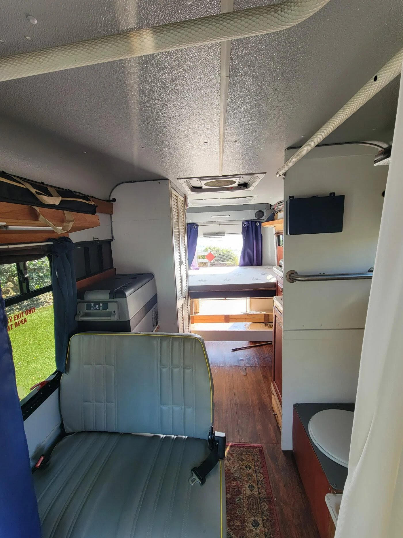 View inside an rv rental: features a bed, comfy seating, fridge, and toilet. A compact interior ideal for travel.. Ford E-Series; Ford E-350 2016