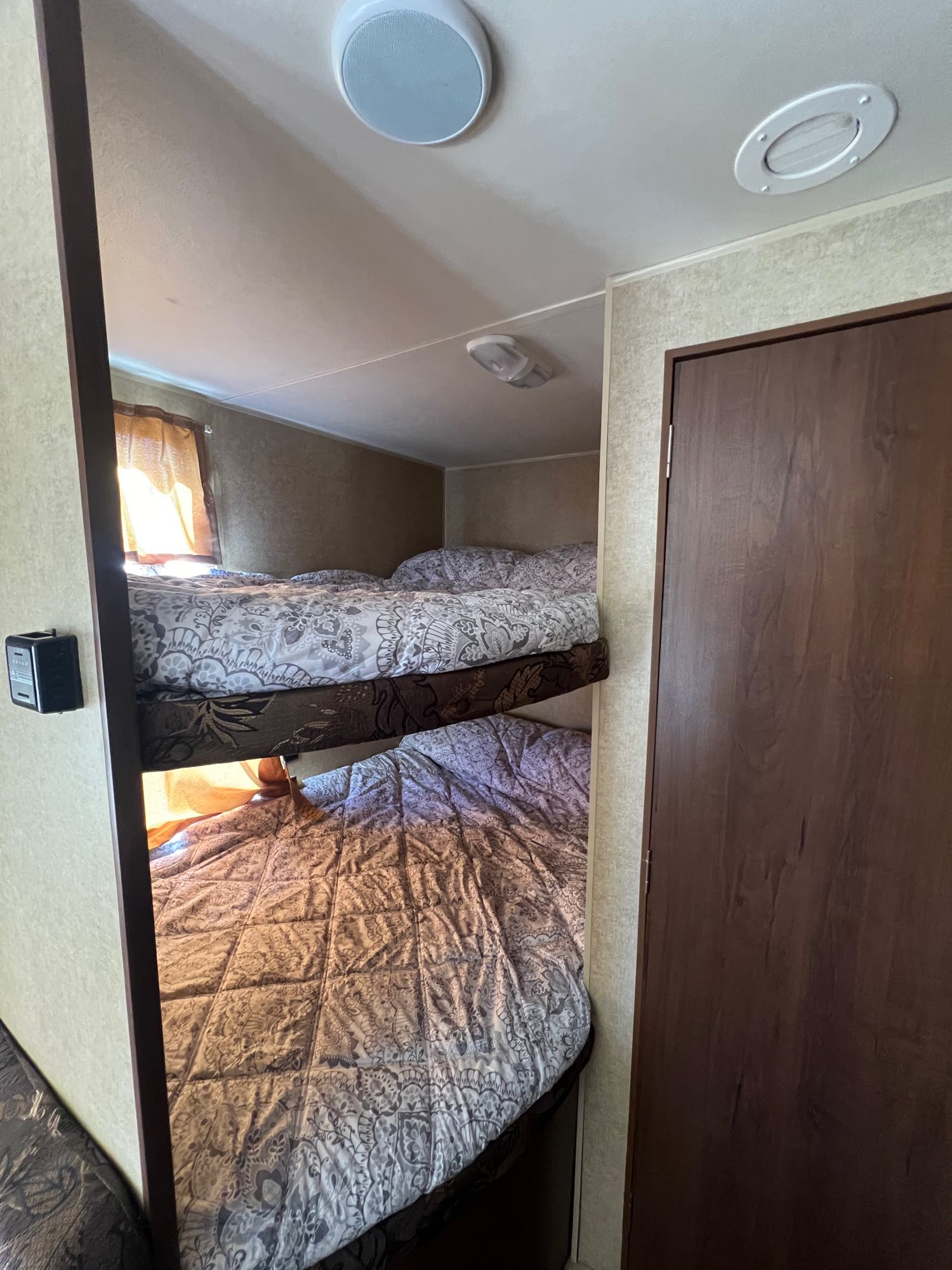 Inside an RV rental: cozy bunk beds with patterned bedding and ceiling lights. A space-saving sleeping solution.. Jayco Jay Flight Swift 2014