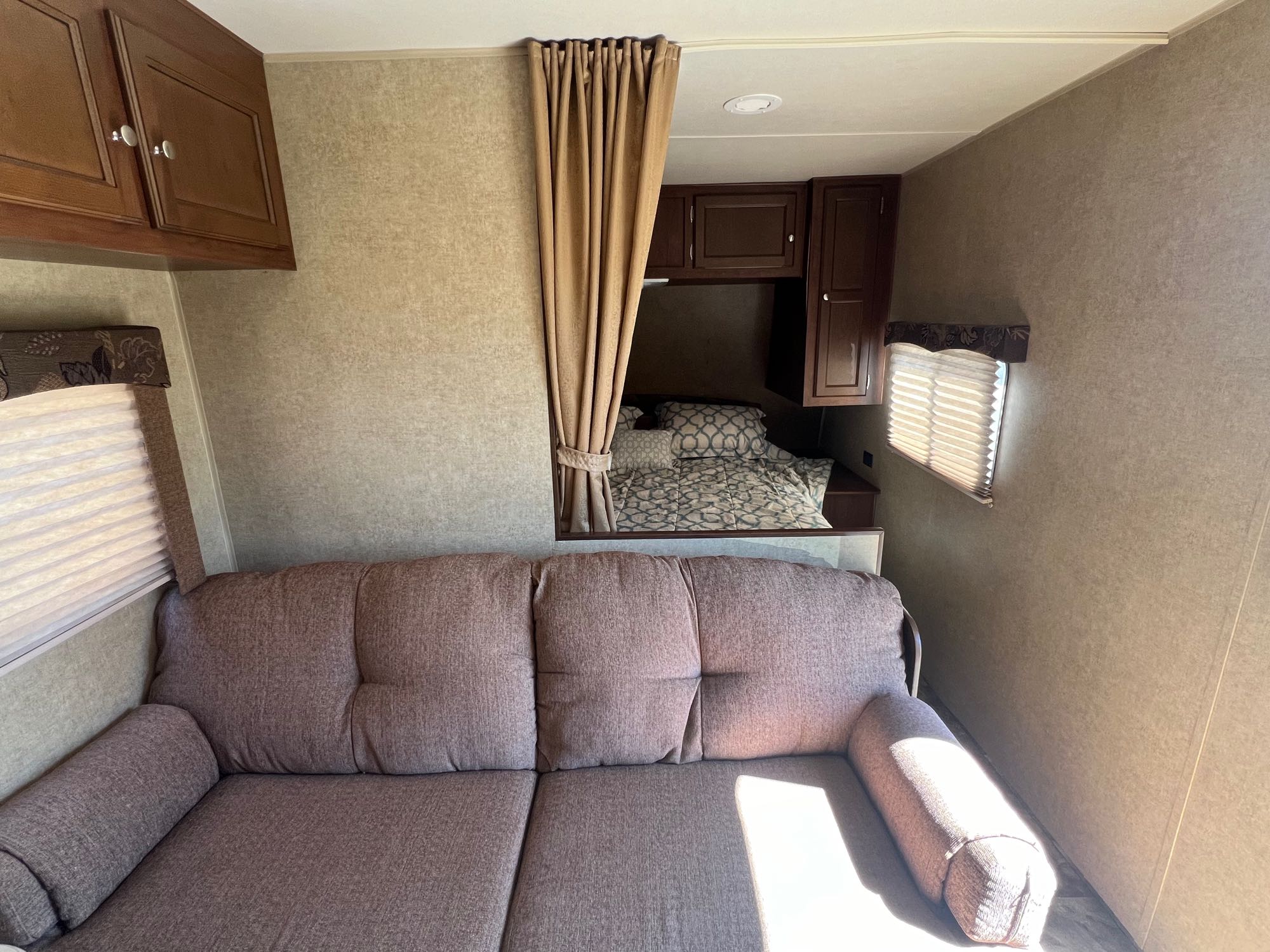 Inside this RV rental: a plush couch in the living area and a partitioned bedroom with a bed, ideal for your next adventure.. Jayco Jay Flight Swift 2014