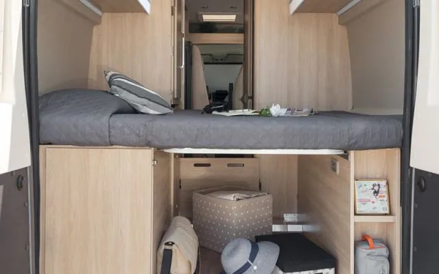 Cozy RV rental interior: A raised bed with under-bed storage, perfect for compact travel.. Giottivan 60T 2024