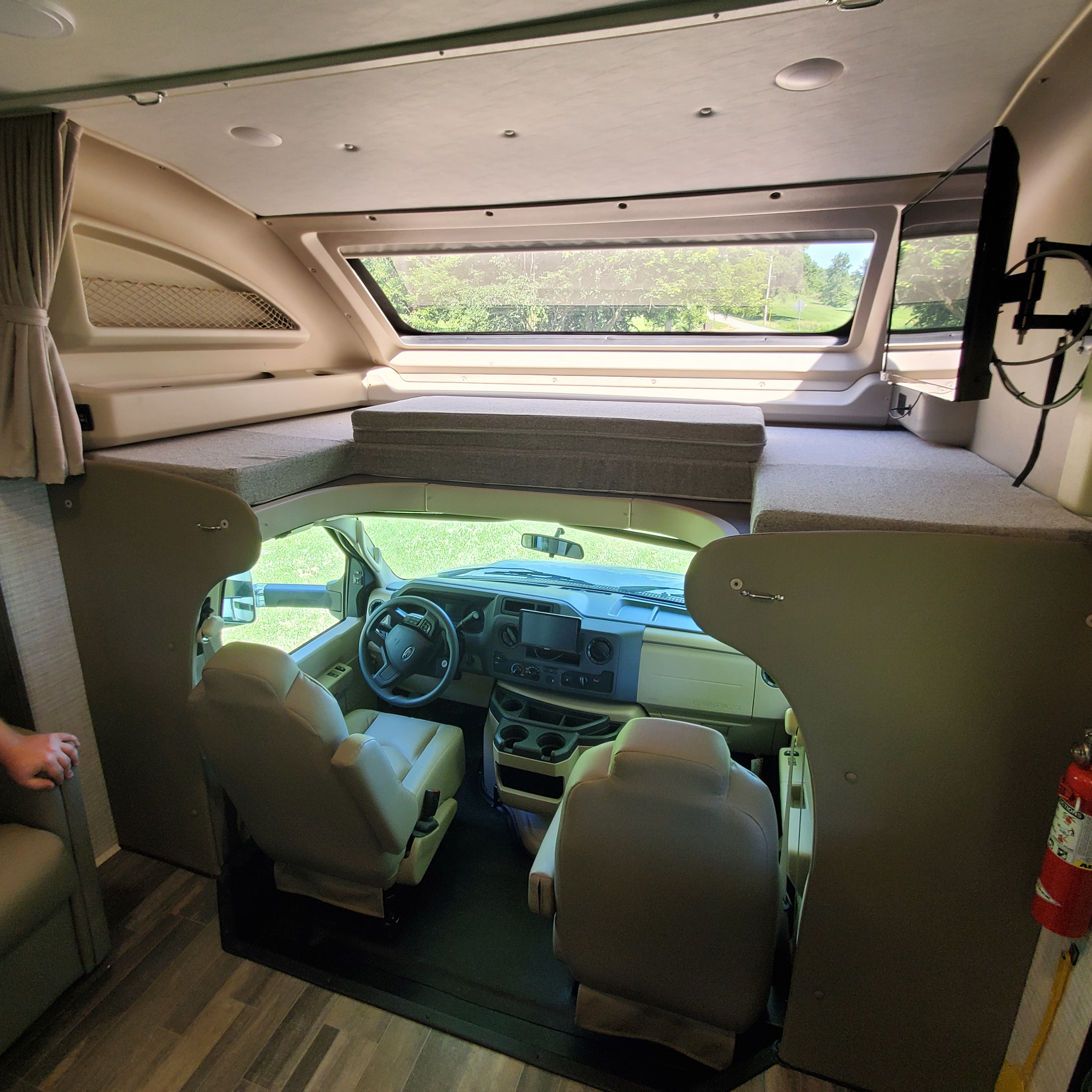 Inside an RV rental: overview of the driver's cockpit, front seats, and the spacious overhead bunk.. Jayco Greyhawk 2024