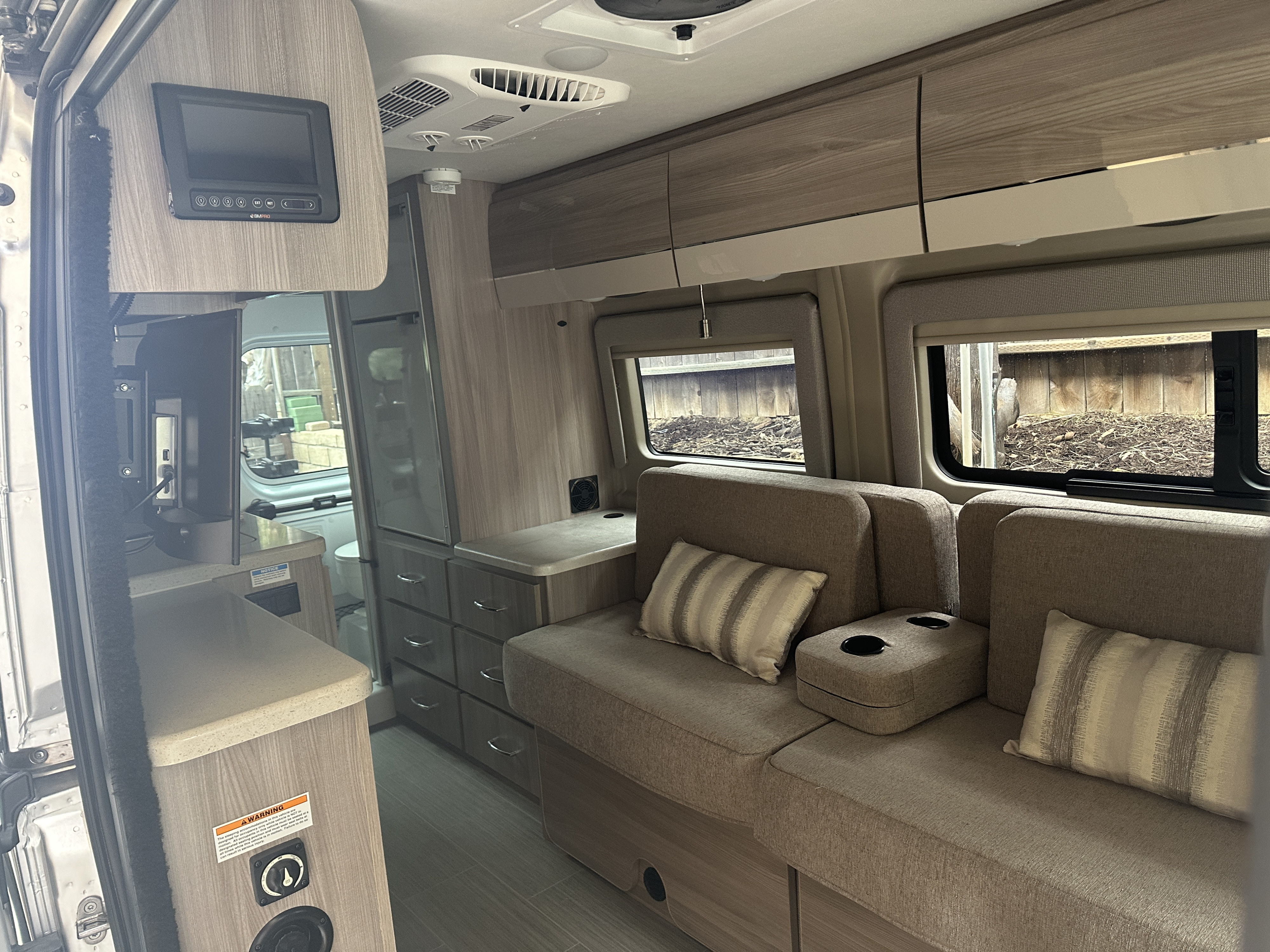 Modern RV rental interior with comfy seating, woodgrain cabinets, and BMPRO controls. Enjoy mobile living convenience!. Thor Sequnce 2023