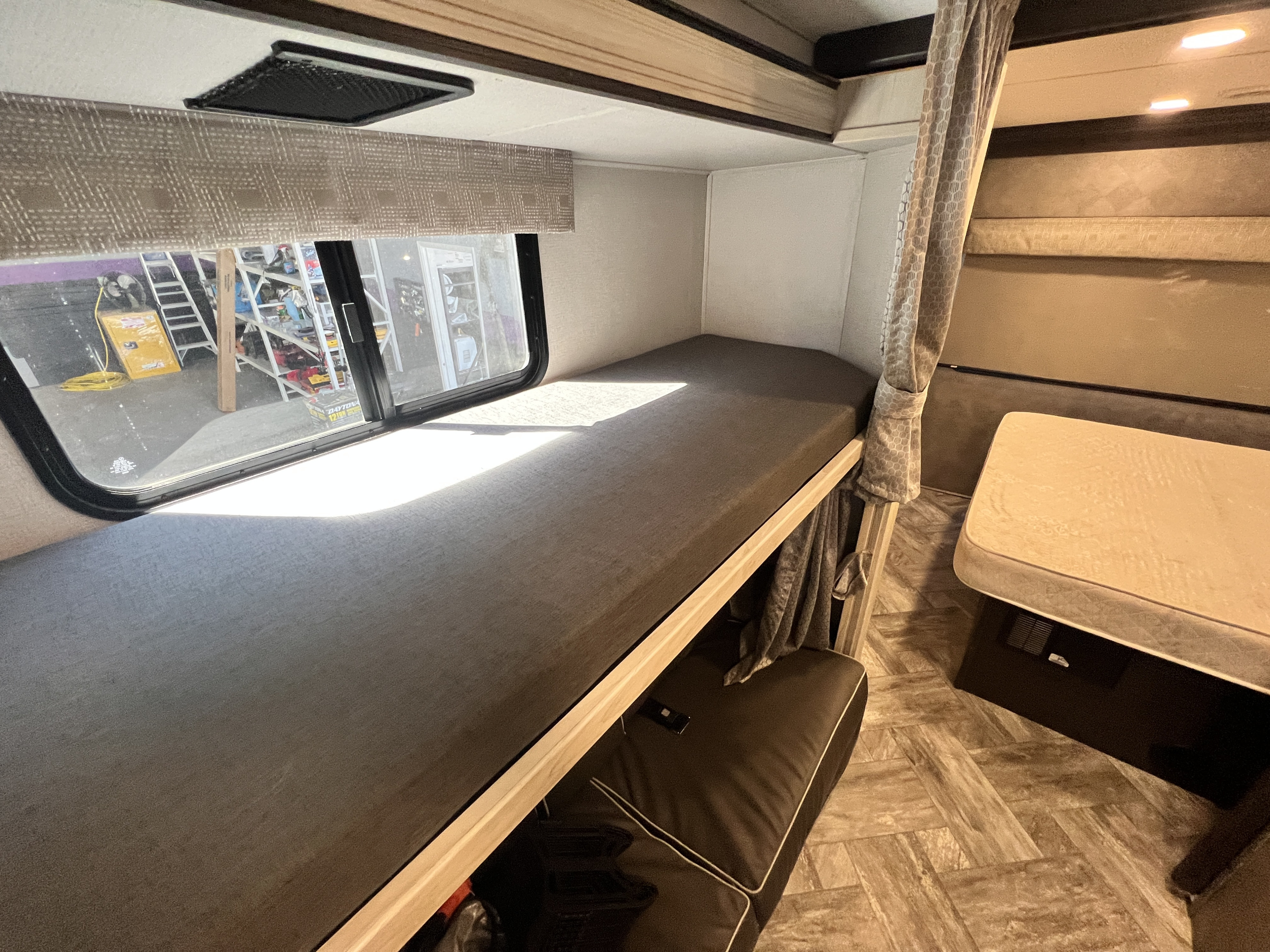 Cozy RV rental interior: bunk beds with a sunlit window, a lower sofa, and a compact dinette for comfortable travel.. Forest River Sunseeker 2023