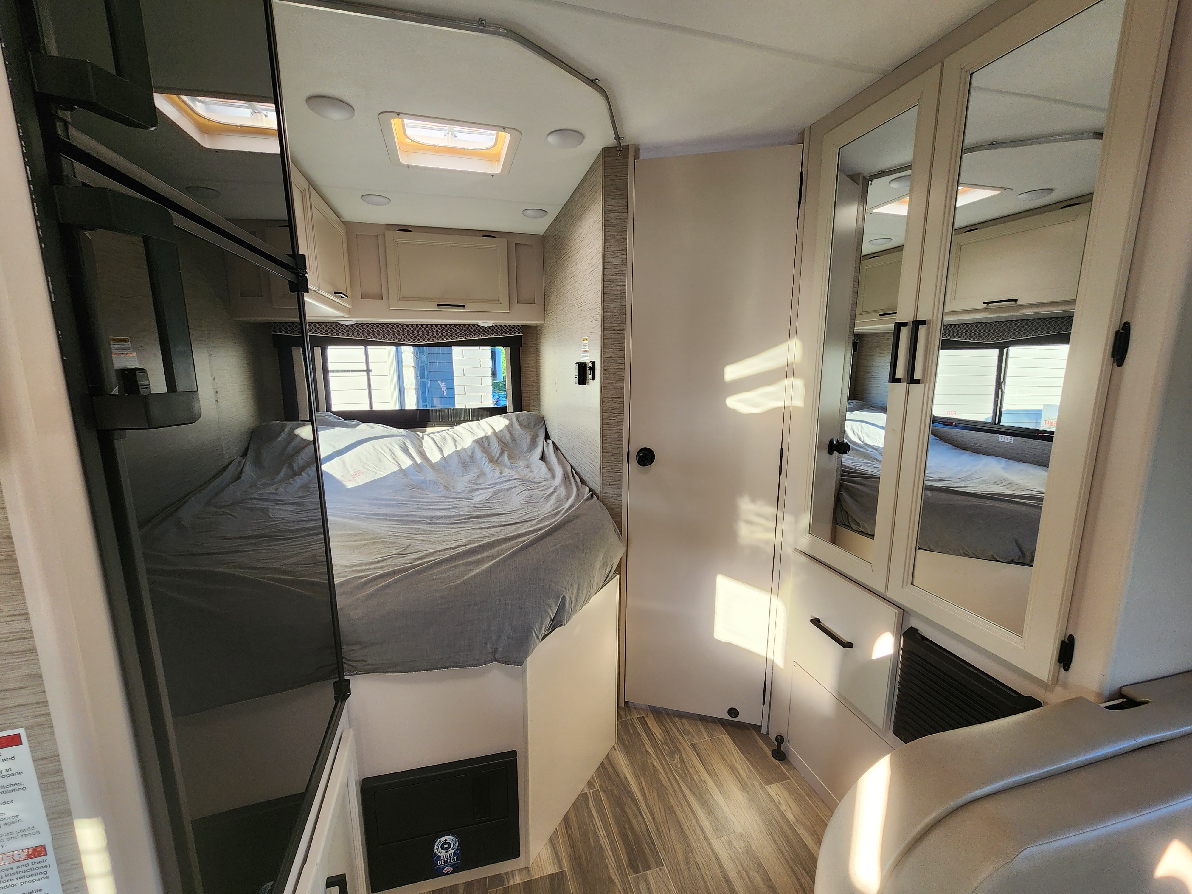 Explore this cozy **rv rental** bedroom. Features a comfortable bed, overhead storage, and mirrored closet doors in a compact space.. Thor Four Winds 2024