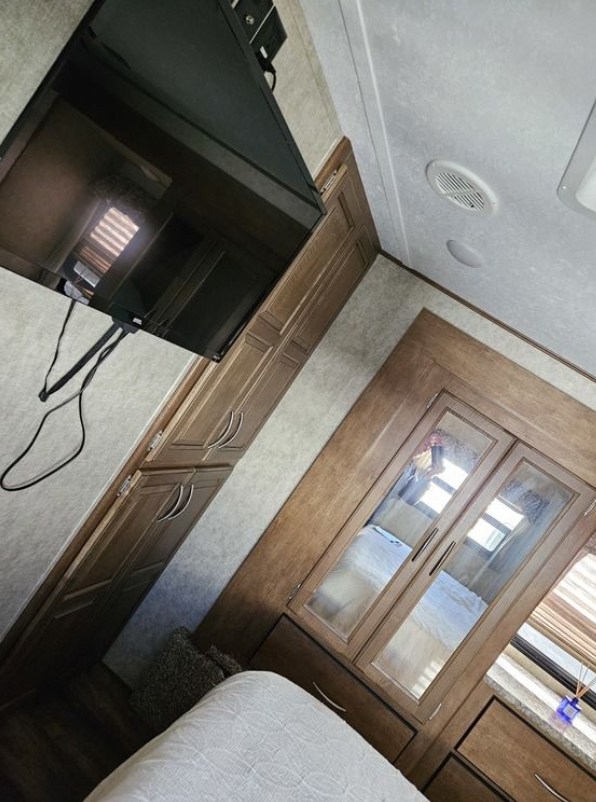 Spacious RV rental bedroom with TV, ample storage, and mirrored wardrobe, perfect for comfortable travel.. Forest River Wildcat 2017
