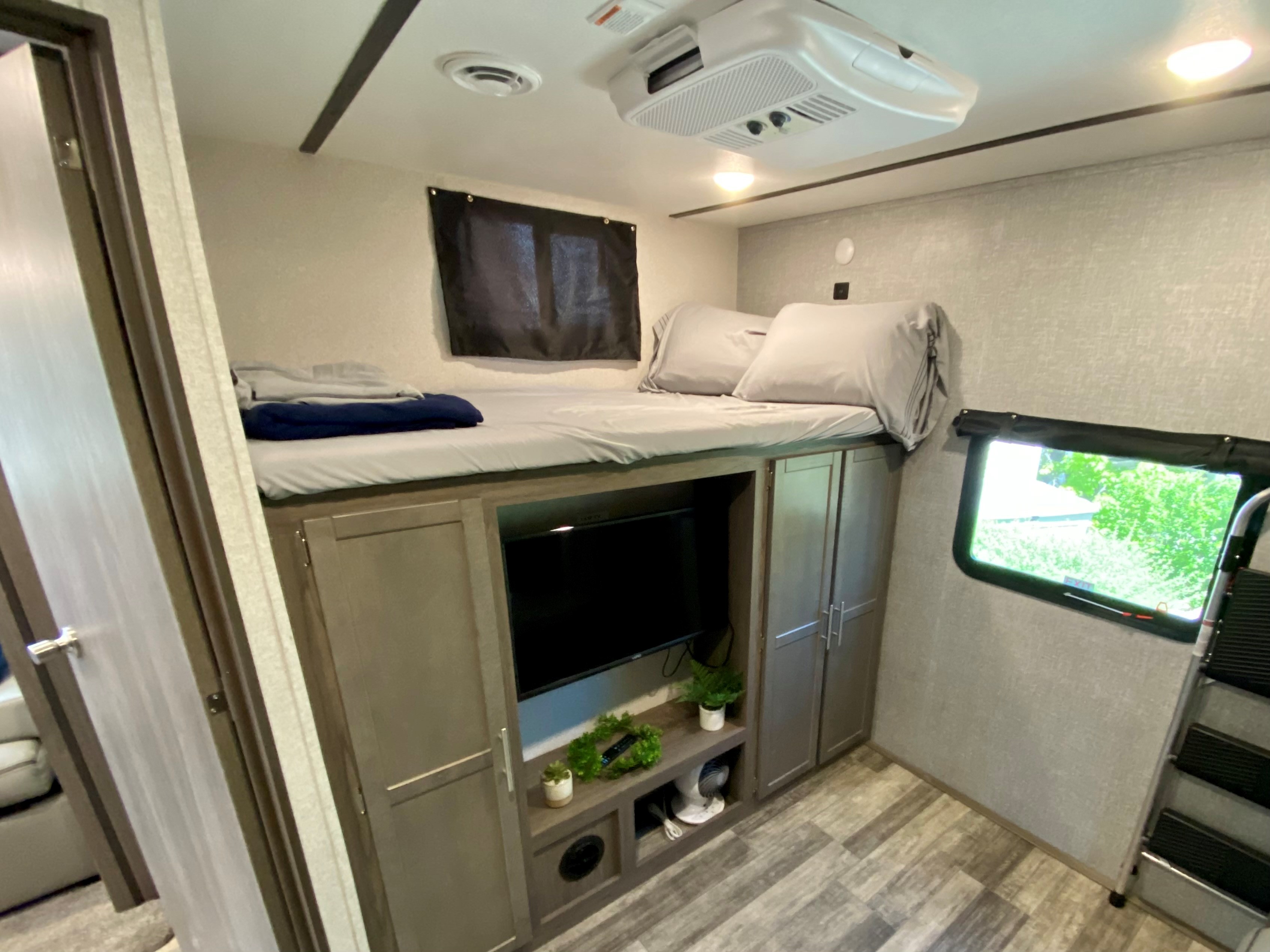 Cozy RV rental interior featuring a bunk bed over a TV unit, storage, and ceiling AC. Ideal for an RV adventure.. Volante 33 2021