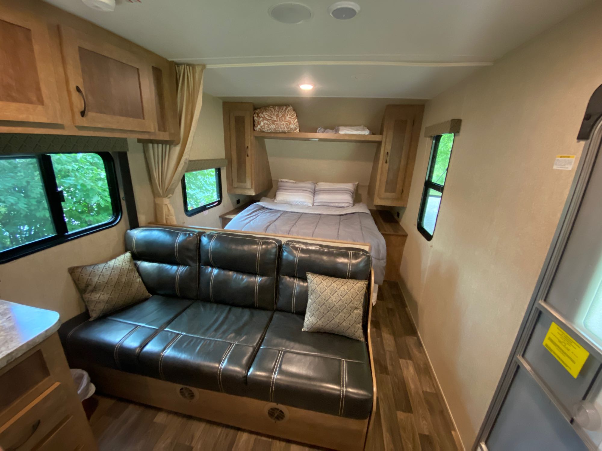 This RV rental interior offers a comfortable bed, overhead cabinets, and a dark sofa, providing a cozy mobile living space.. Starcraft AR-One Maxx 2017