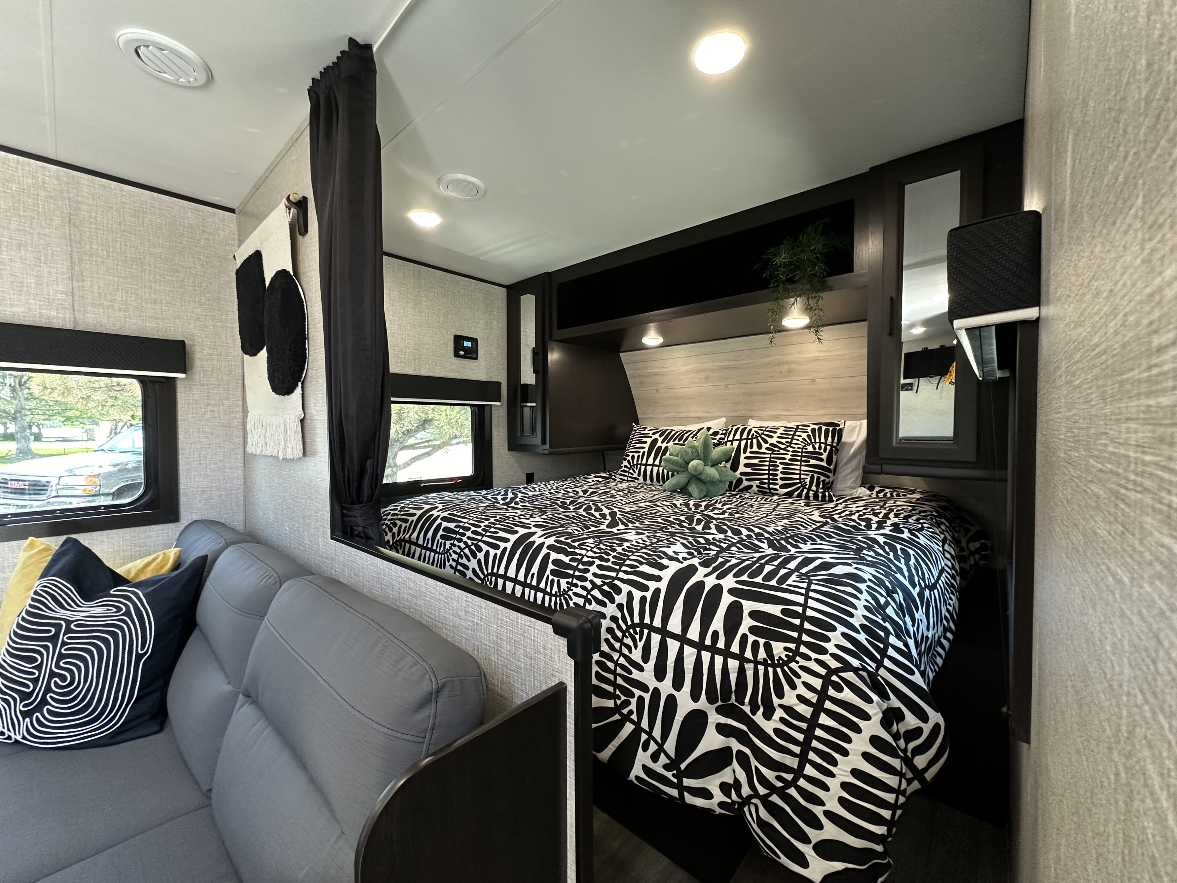 This RV rental offers a modern interior, showcasing a comfy bedroom with bold black & white bedding and a cozy sofa area.. Jayco Jay Flight SLX Baja Edition 2023