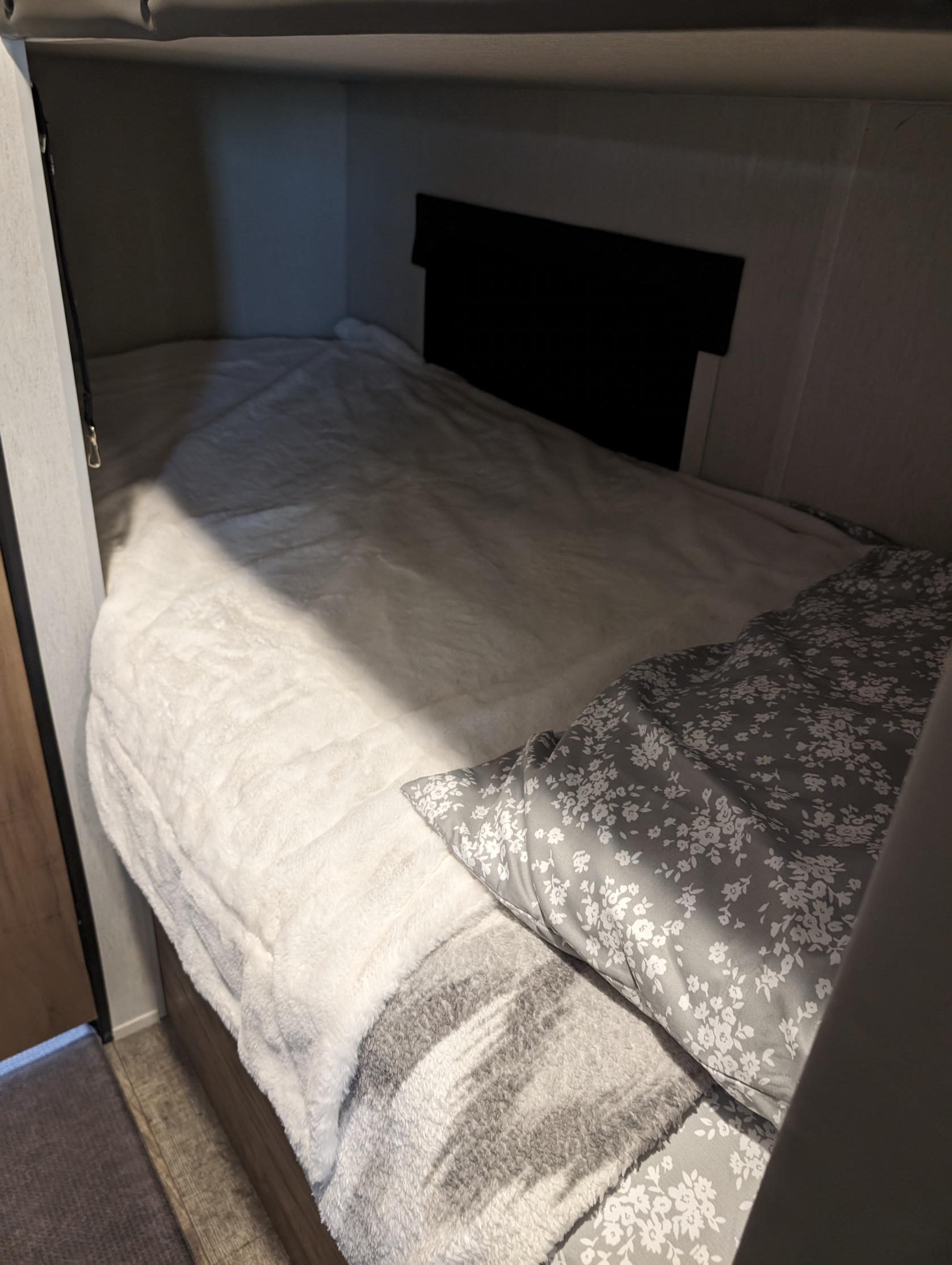 Comfortable RV rental bunk bed with soft white and floral bedding, perfect for a cozy sleep.. Forest River Cherokee Wolf Pup 2023