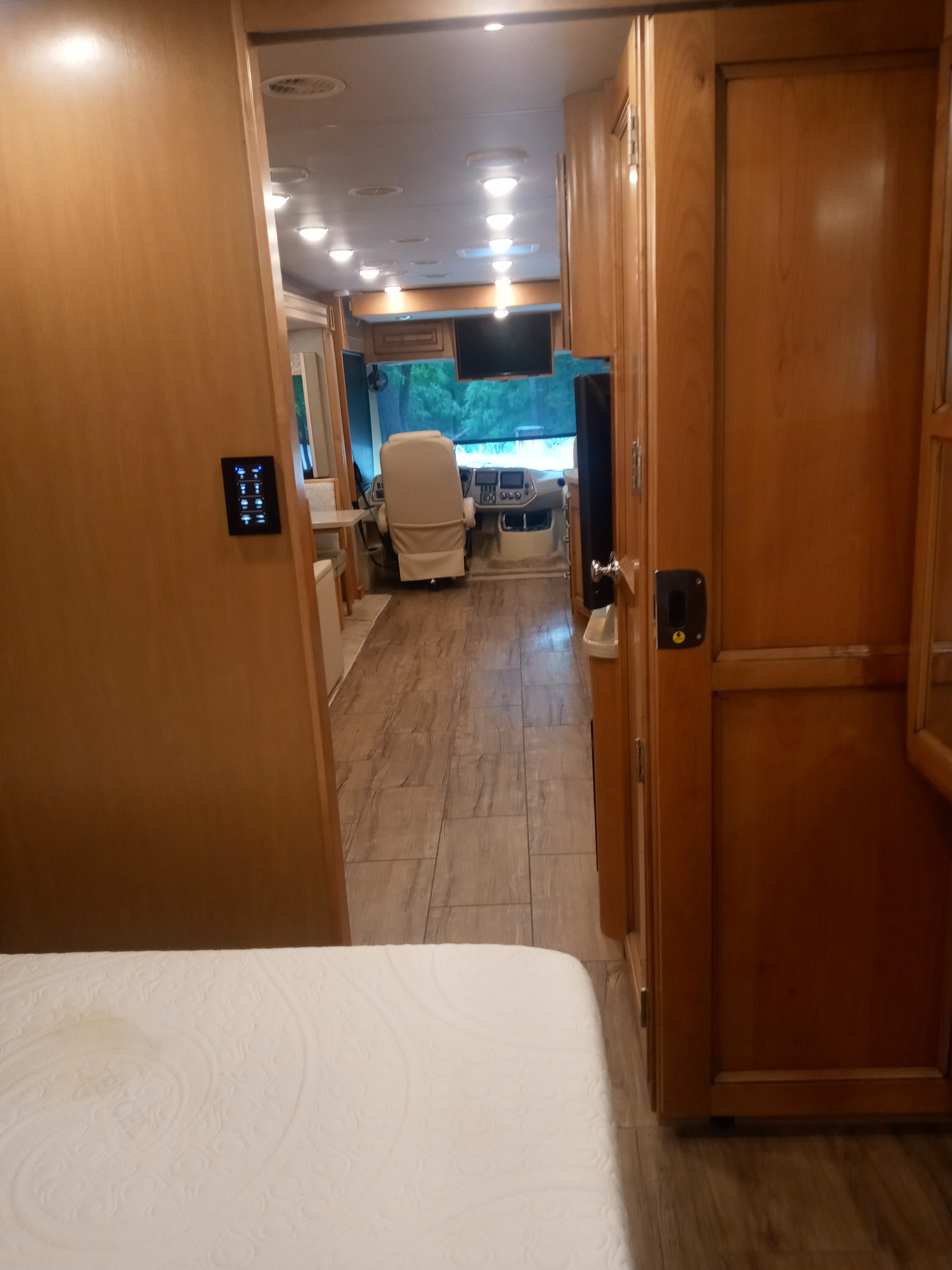 Spacious RV rental interior with wood-look flooring, leading from the bedroom to the cockpit area.. Tiffin Open Road Allegro 36 foot 2019