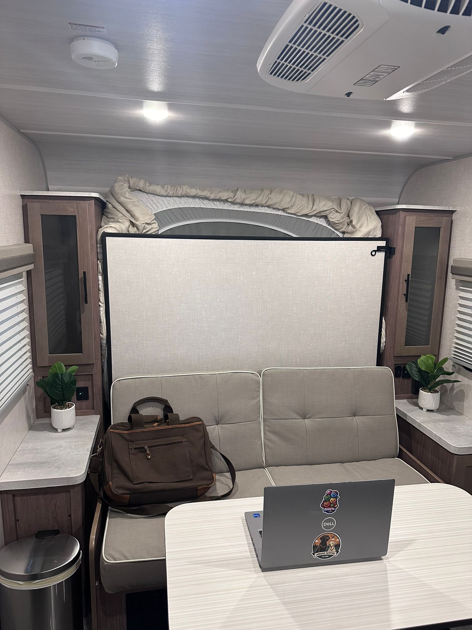 This RV rental showcases a functional interior with a dinette, sofa, and a hidden bed above, serving as a cozy workspace.. No Boundaries 19 2023
