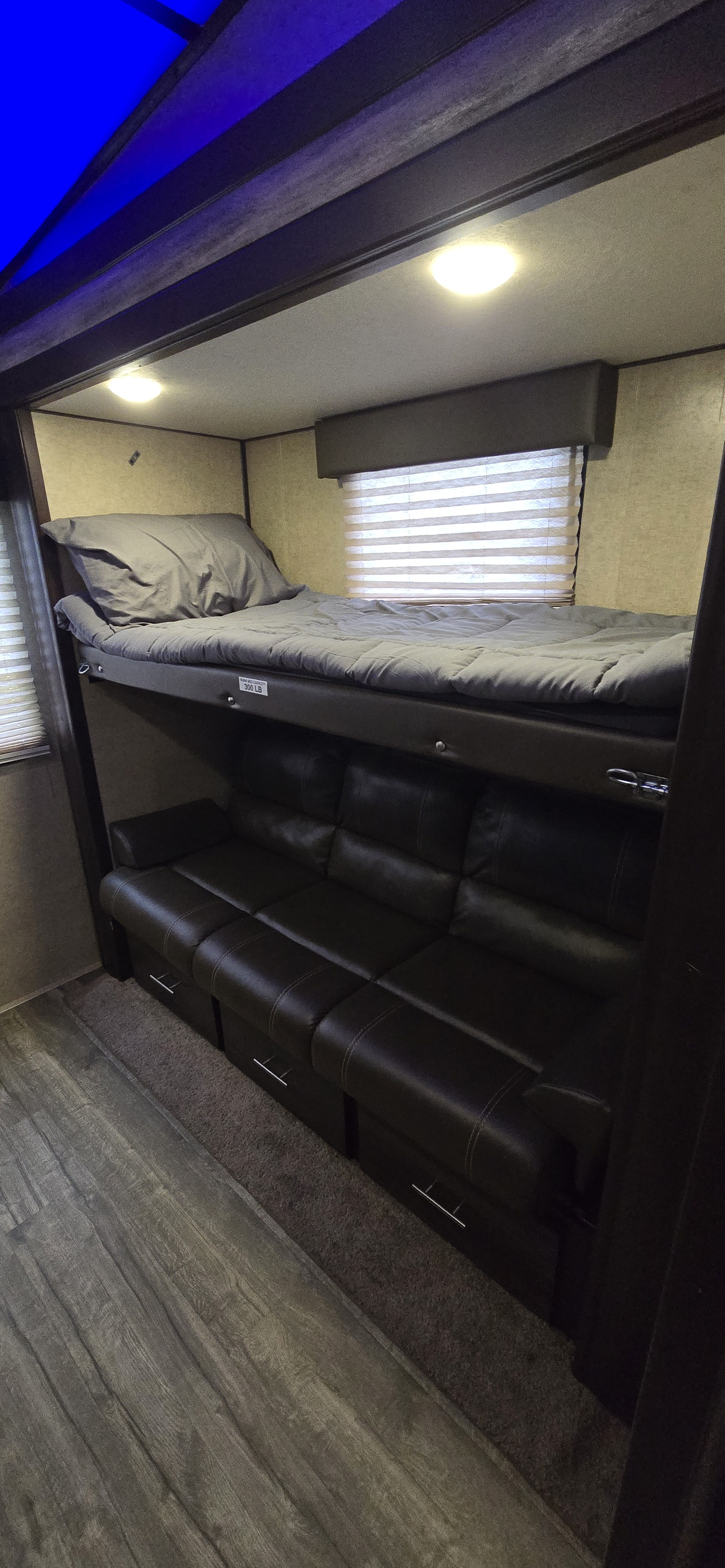 RV rental bunkhouse. Upper bunk bed (300 lb limit) over a convertible dark leather sofa with storage. Wood-look floor.. Forest River Cherokee Arctic Wolf 2018