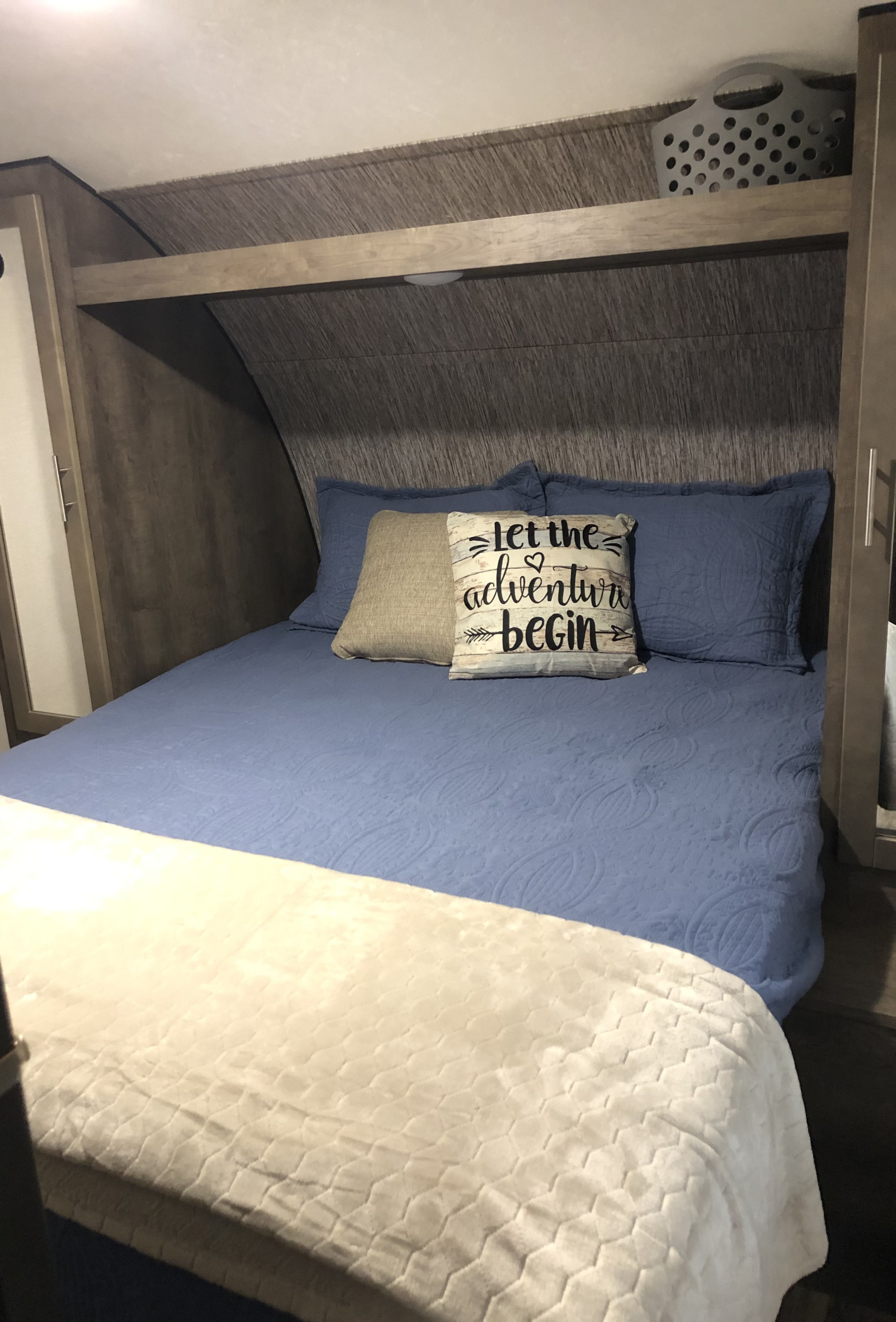 Cozy RV rental bedroom featuring a blue bed with "Let the adventure begin" pillow, and overhead storage.. KZ Connect SE C231RBKSE 2019