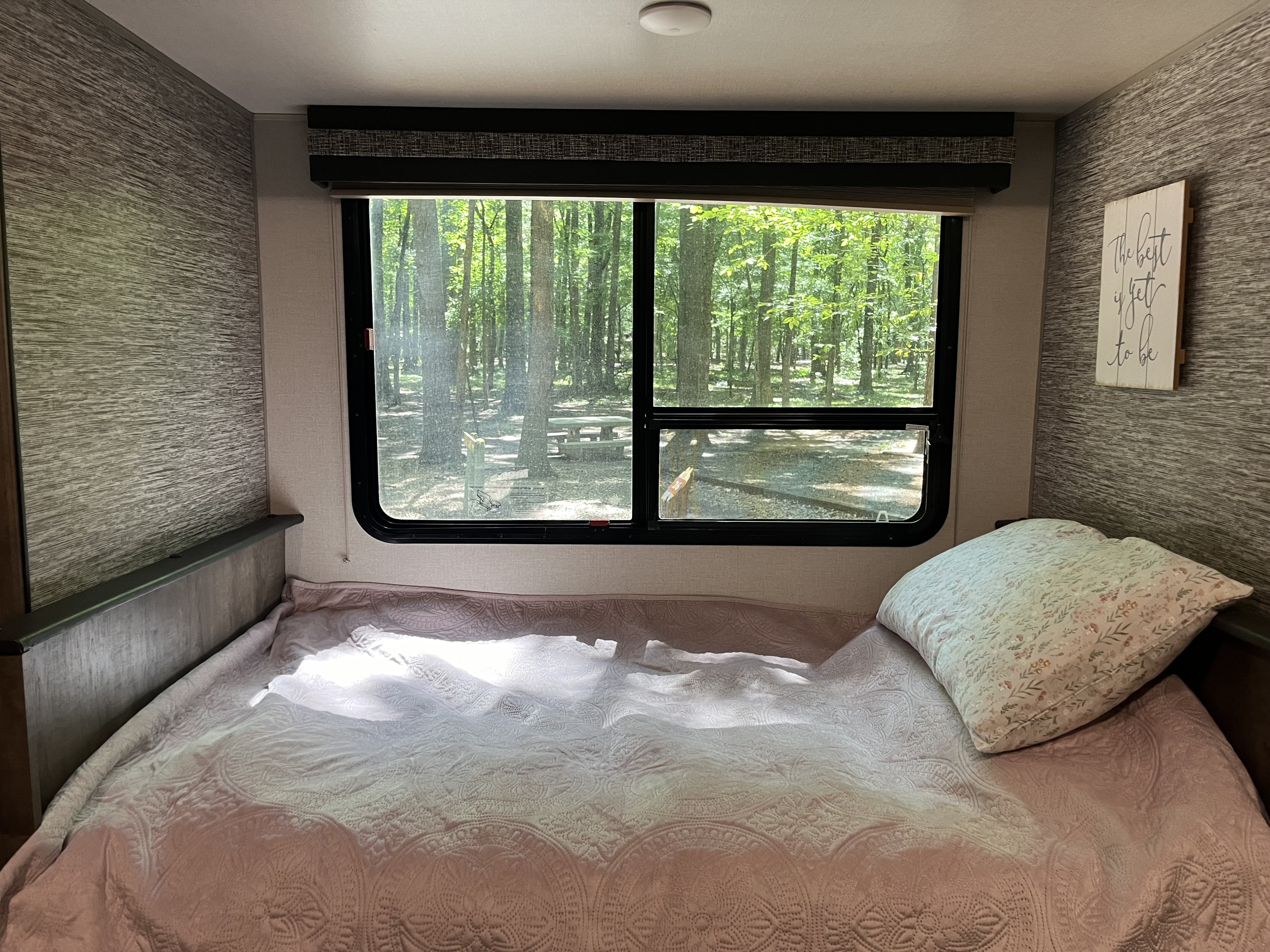 Peaceful RV rental bedroom with a comfortable bed, overlooking a serene forest campsite. Natural light fills the space.. KZ Connect SE C231RBKSE 2019