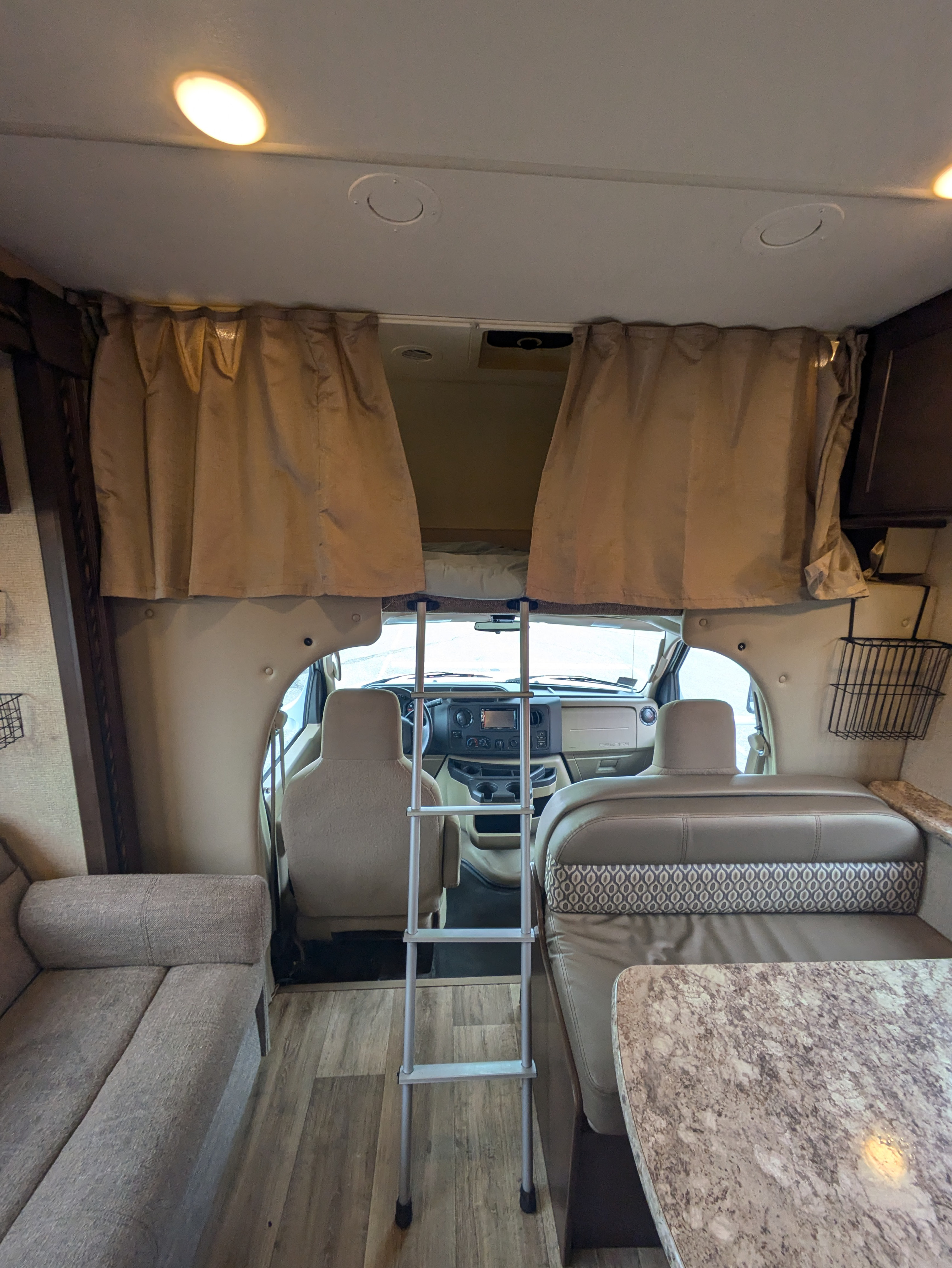 Spacious RV rental interior: Ladder accesses the overhead bunk. Features include a sofa, dinette, and cockpit view.. Thor Freedom Elite 2018