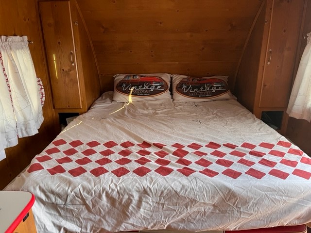 RV rental bedroom: a cozy space with a double bed, red checkered duvet, and Vintage Cruiser pillows, set within a warm wooden interior.. Gulf Stream Vintage Cruiser 2021
