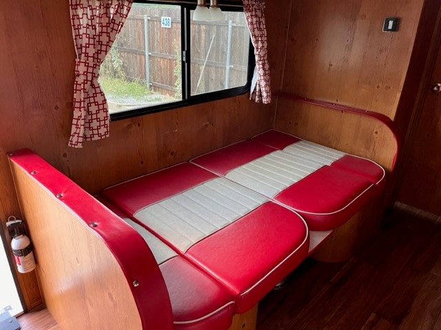 Explore this charming vintage RV rental interior, featuring a cozy red and white dinette booth and wood-paneled walls.. Gulf Stream Vintage Cruiser 2021