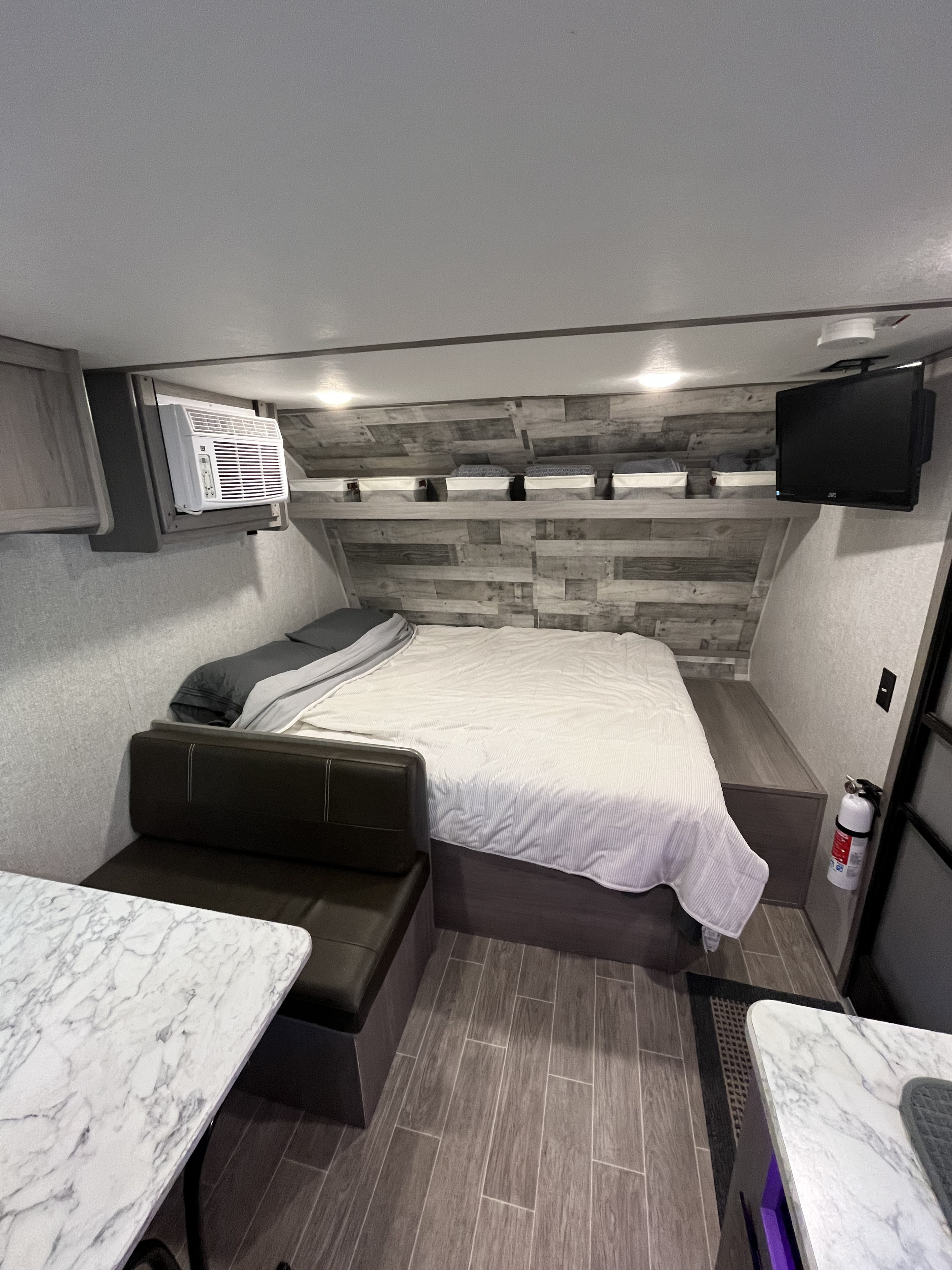 Inside a compact RV rental: a comfy bed, dinette, AC unit, and TV create a functional, cozy living space.. Dutchmen Coleman Lantern LT 2022