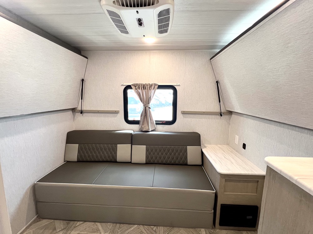 Explore a comfortable RV rental interior: convertible dinette, overhead storage, AC, and window create a cozy space.. Forest River Salem Cruise Lite Platinum 2024